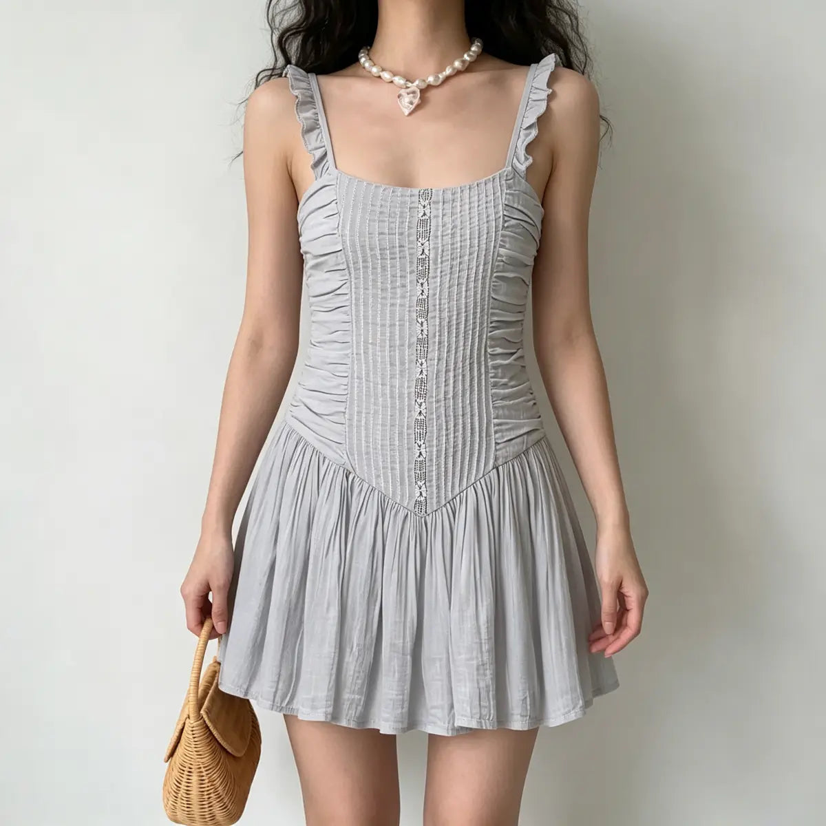 Full front view of a model wearing a light gray ruched mini dress, showing the central lace panel and flared skirt.