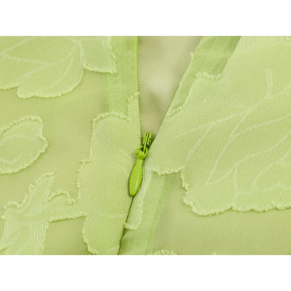 Macro close-up of green invisible back zipper on light green floral jacquard maxi dress