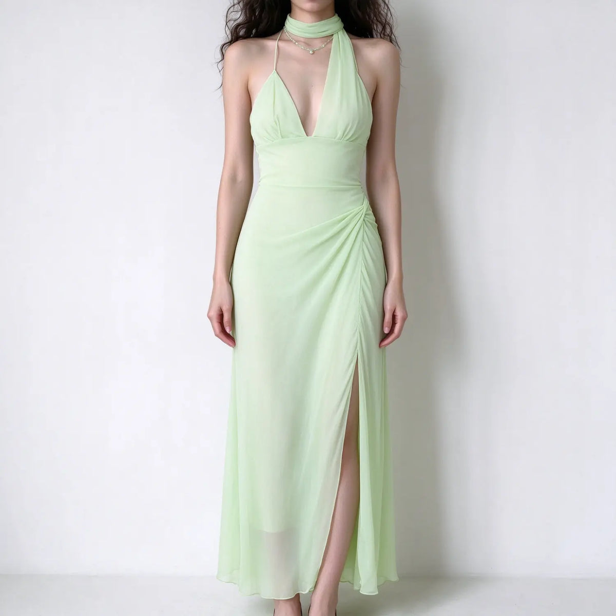 Female model front view wearing light green halter chiffon maxi dress, deep v neck, ruched waist, high side slit, sheer flowy long skirt
