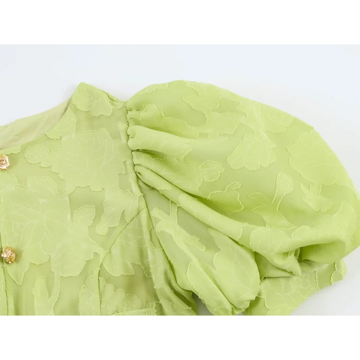 Close-up of voluminous puff short sleeve on light green jacquard maxi dress, raised floral texture fabric