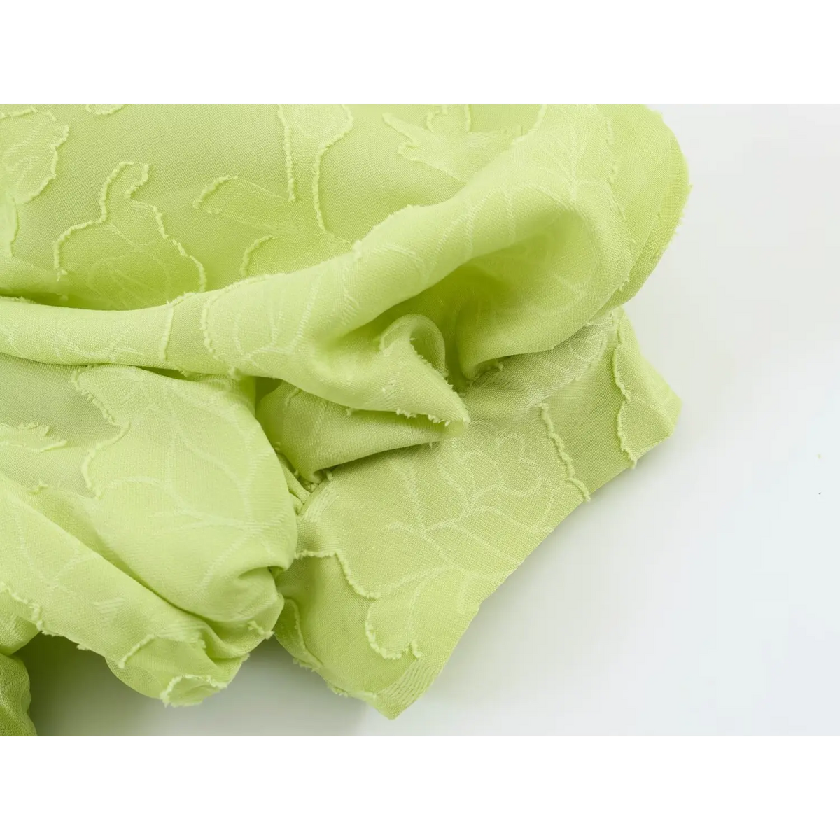 Close-up crumpled shot of light green floral jacquard fabric with raw edge rose pattern for maxi dress