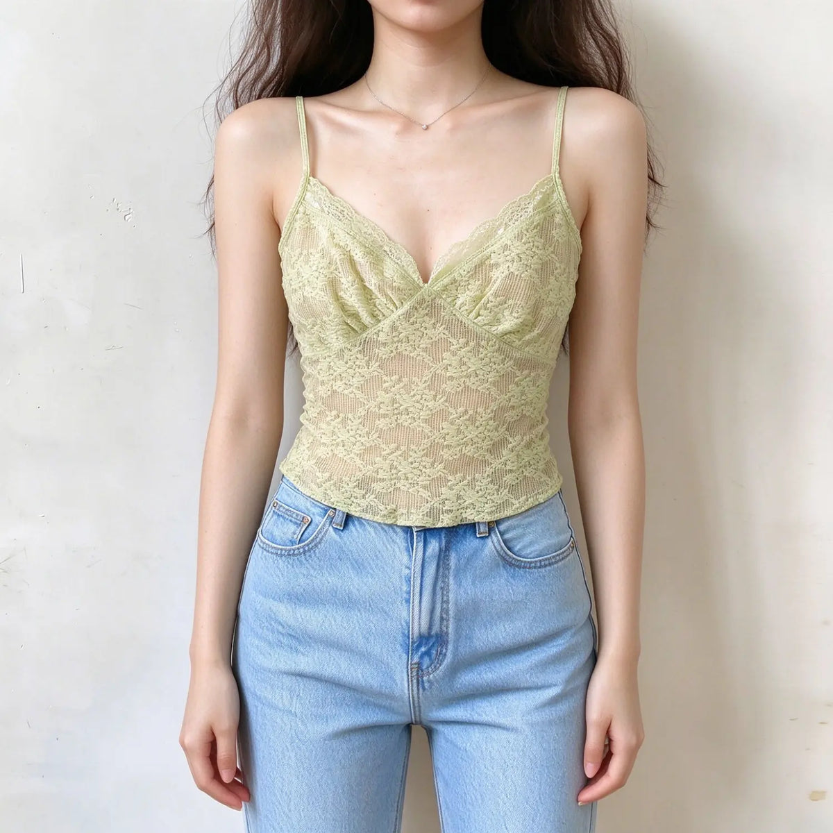 Model wearing light green lace camisole top, v-neck with scalloped lace trim, floral lace pattern, thin spaghetti straps, slim fitted silhouette