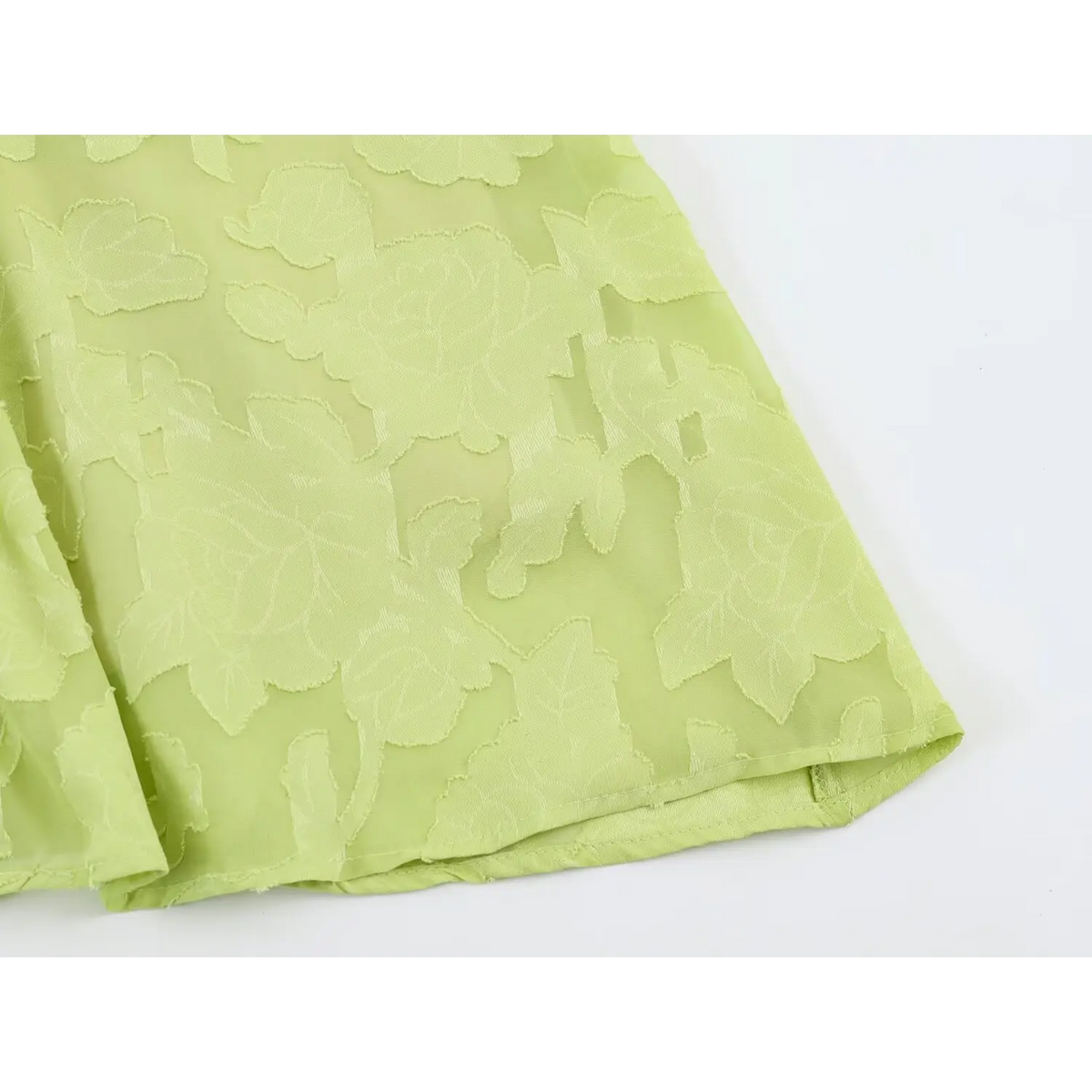 Close-up of maxi dress skirt hem, light green raised floral jacquard fabric and neat bottom seam