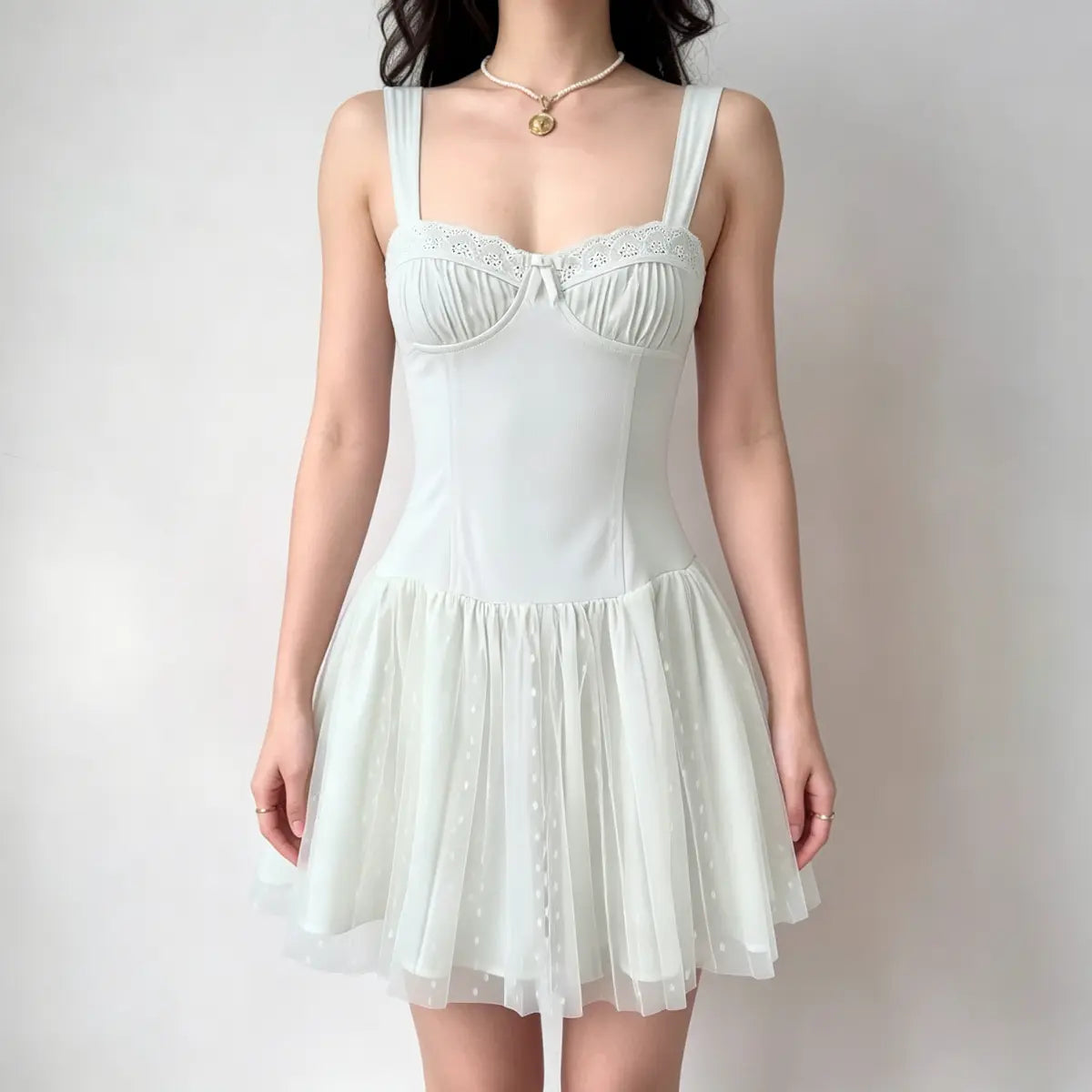 Model wearing a light green corset-style dress with a lace-trimmed bustier, gathered tulle skirt, and wide straps.