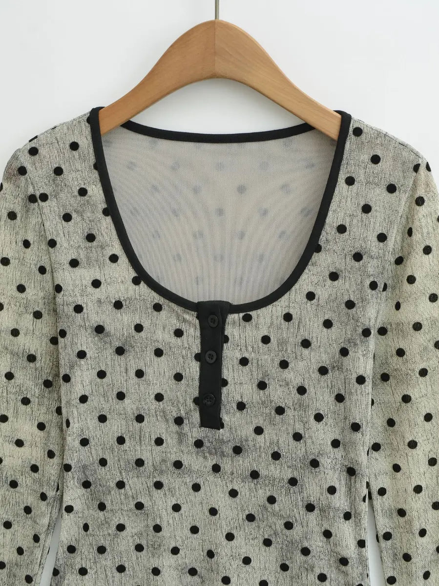 Close-up of the scoop neckline and henley-style button placket on the light grey polka dot long-sleeve top