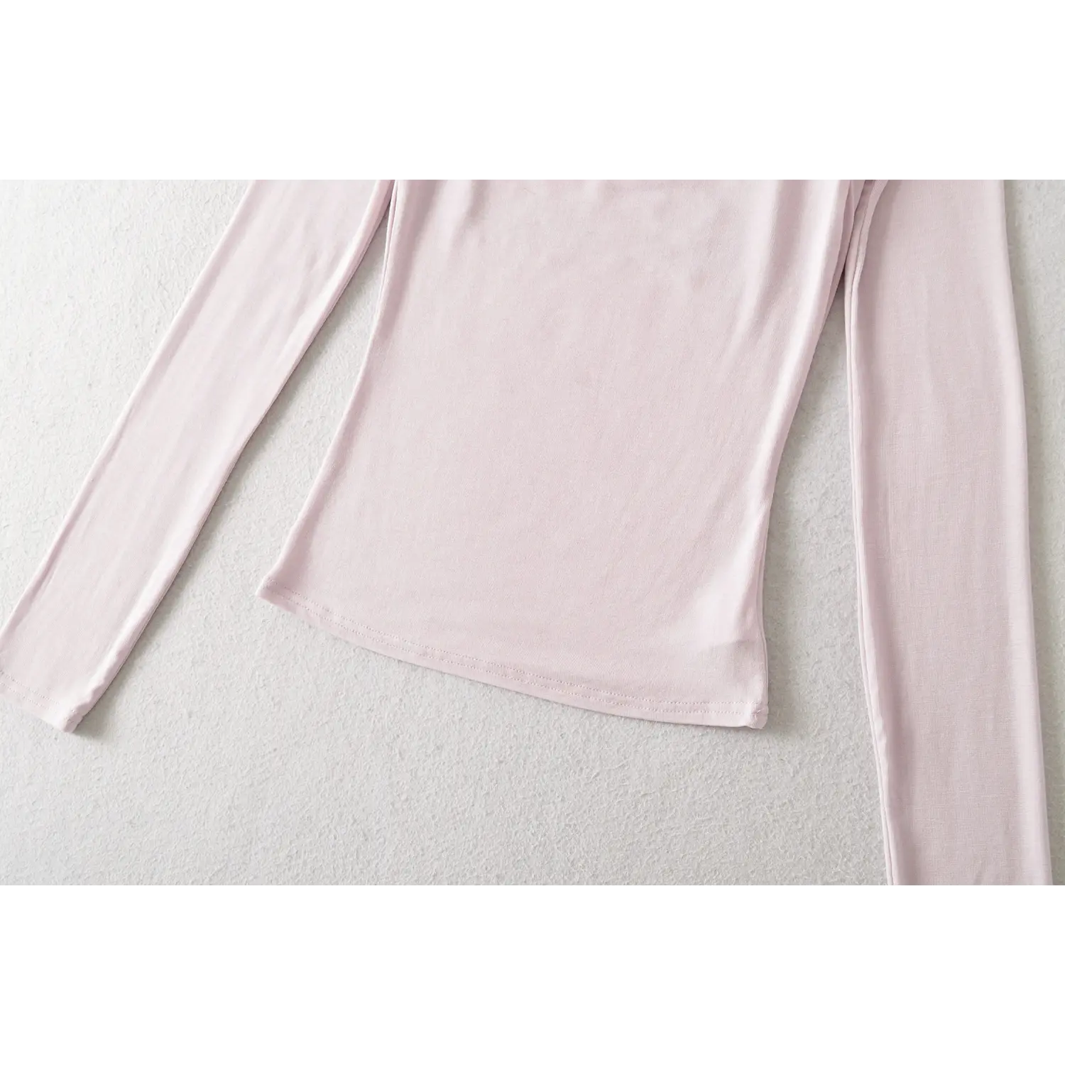 Light lilac fake two long sleeve top hem flat close-up, neat double line overlock waist soft modal knit fabric edge binding stitching white background shot