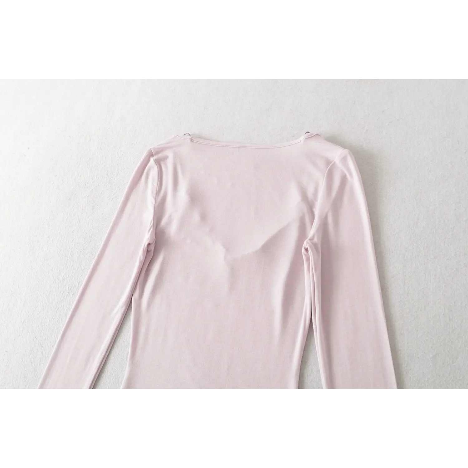 Light lilac fake two long sleeve top back neck flat close-up, thin strap root reinforced stitching crew neck binding overlock smooth knit fabric white background craft shot