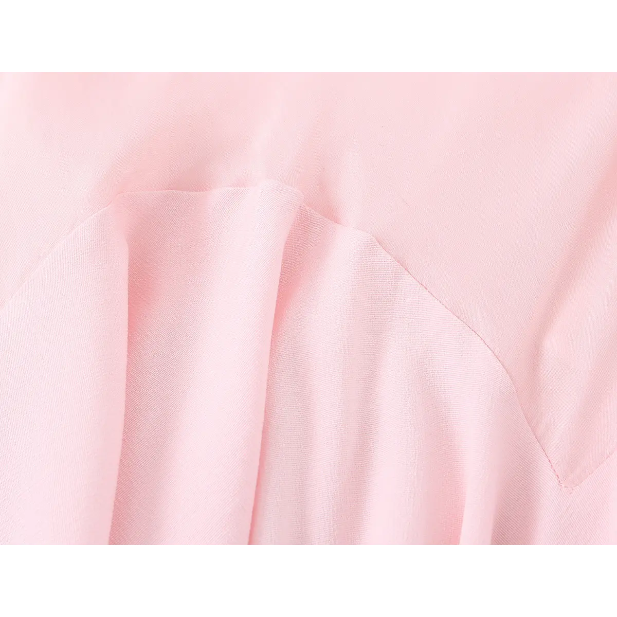 Close-up of the diagonal seam and ruffled panel construction on the light pink cami dress