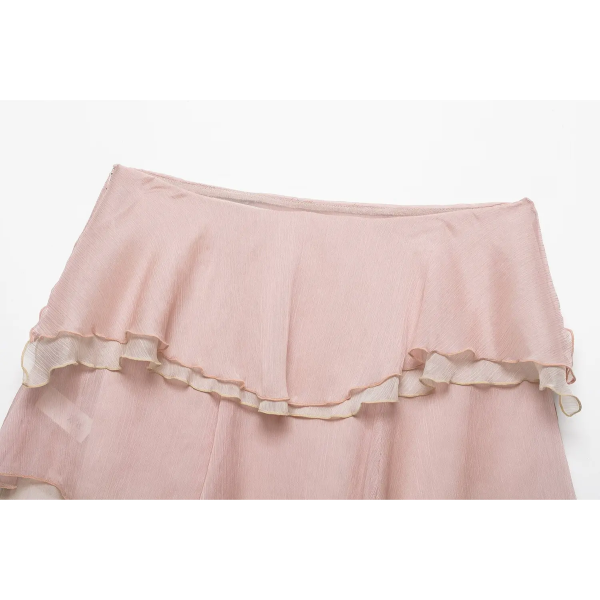 Top view of light pink tiered ruffle chiffon mini skirt waistband, soft crinkled fabric and frill details, white background