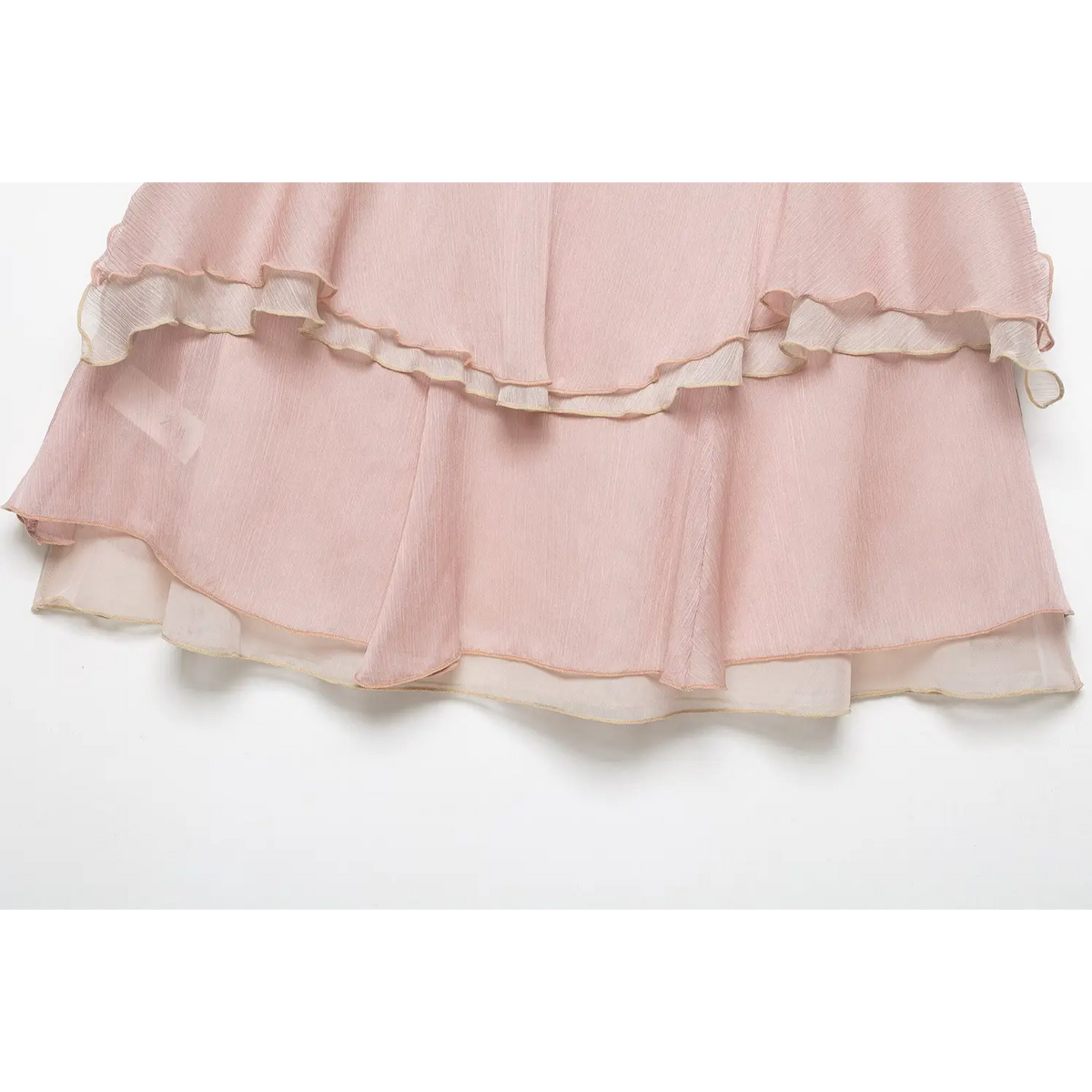 Flat lay full hem view of light pink sheer chiffon mini skirt, multi-tier ruffle hem with contrast piping, white background