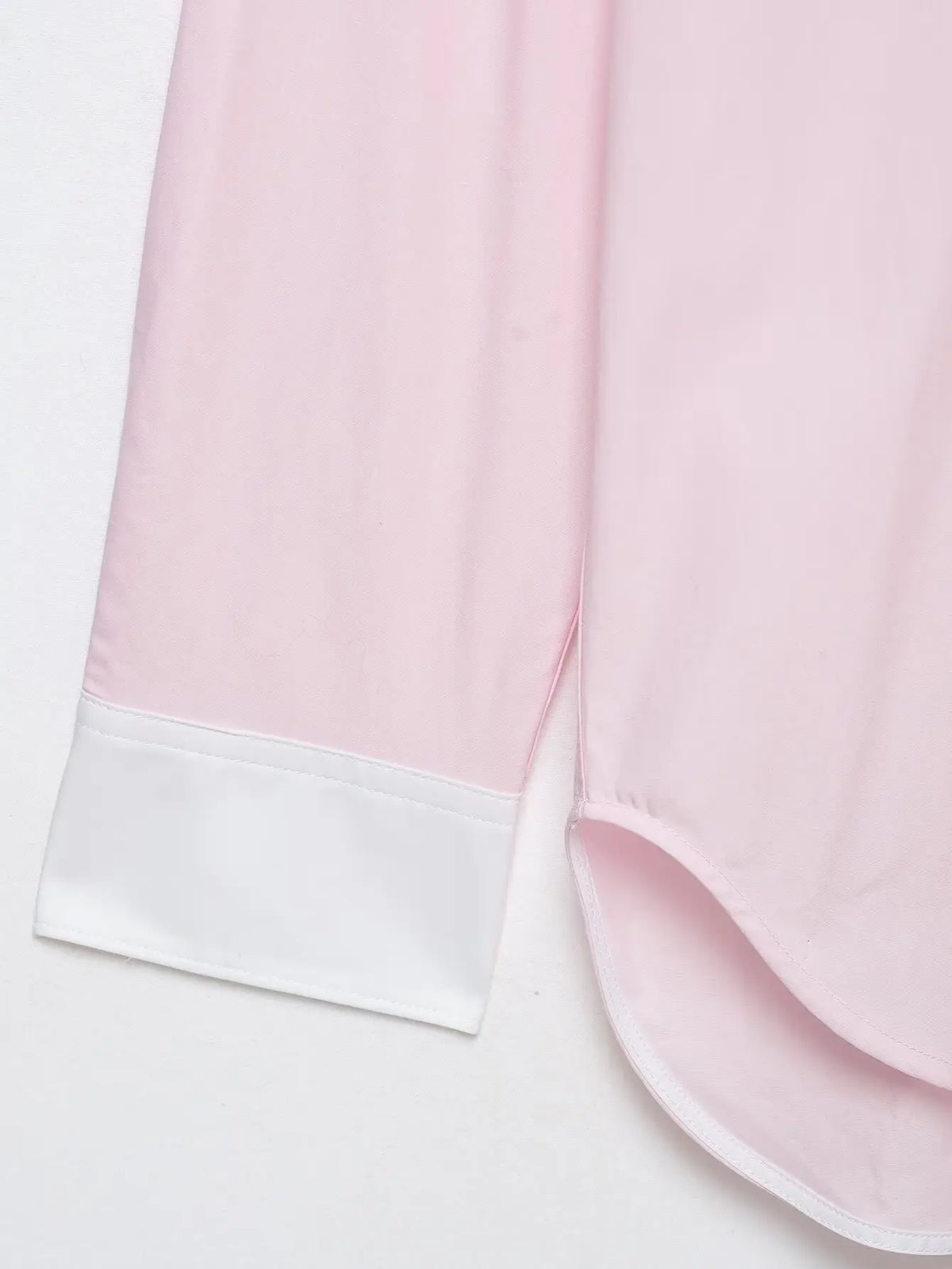 Close-up of white contrast cuff and curved hem