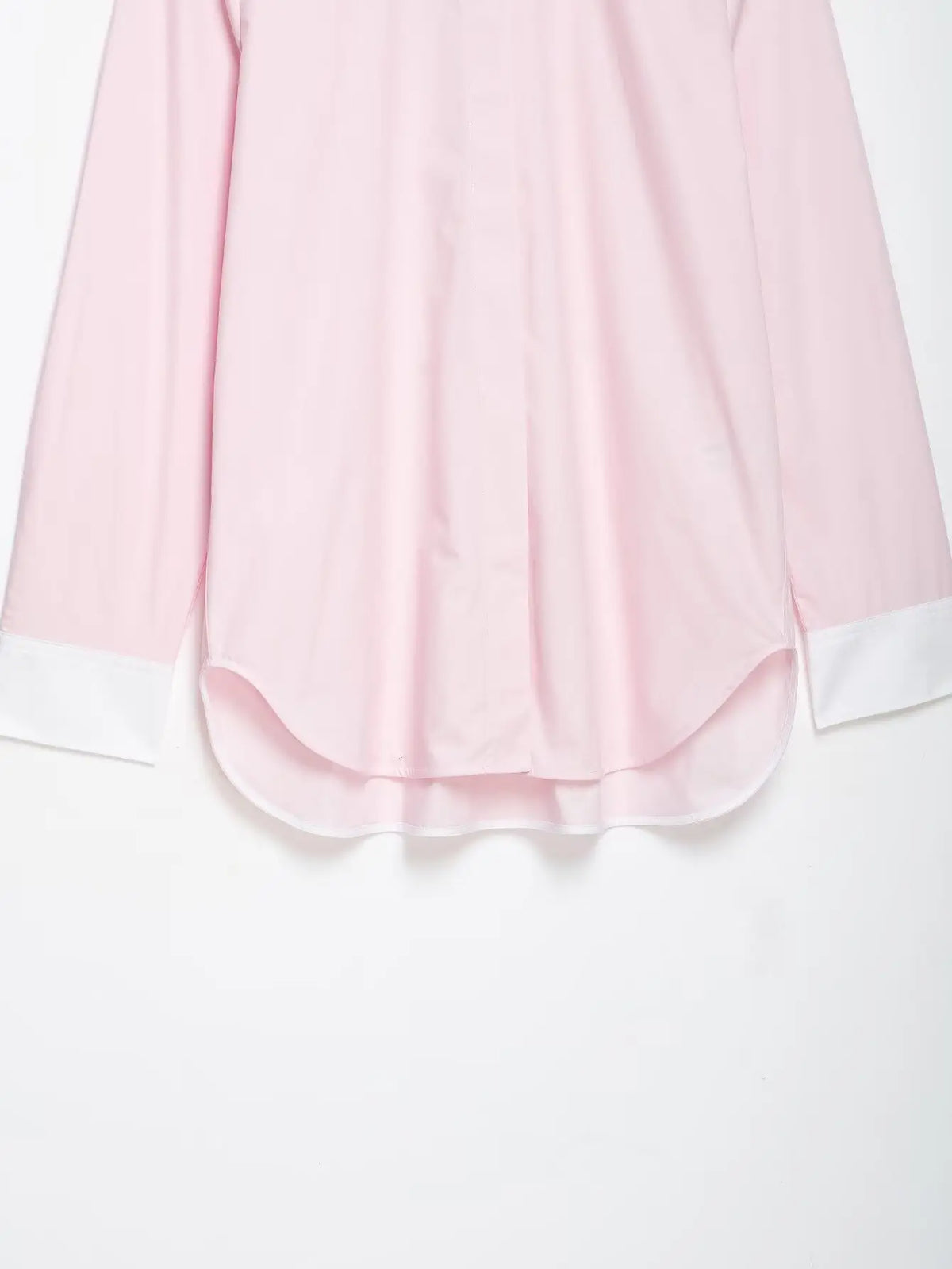 Close-up of curved shirt hem and white cuffs