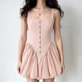 Full-body shot of a woman wearing a light pink corset-style dress with a bubble hem and eyelet details.