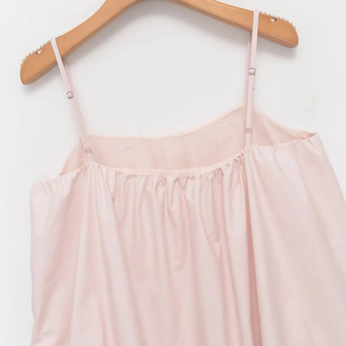 Back view of the light pink cotton dress, showing the adjustable spaghetti straps, gathered neckline, and smooth fabric texture
