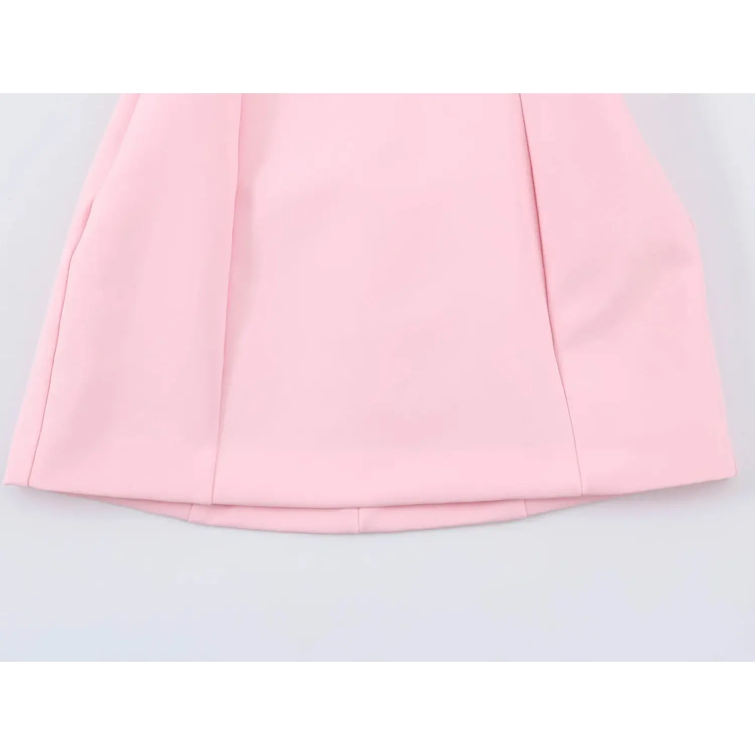 Bottom flared skirt hem close-up, vertical side panel stitching, double layer smooth pink fabric, neat folded hem edge