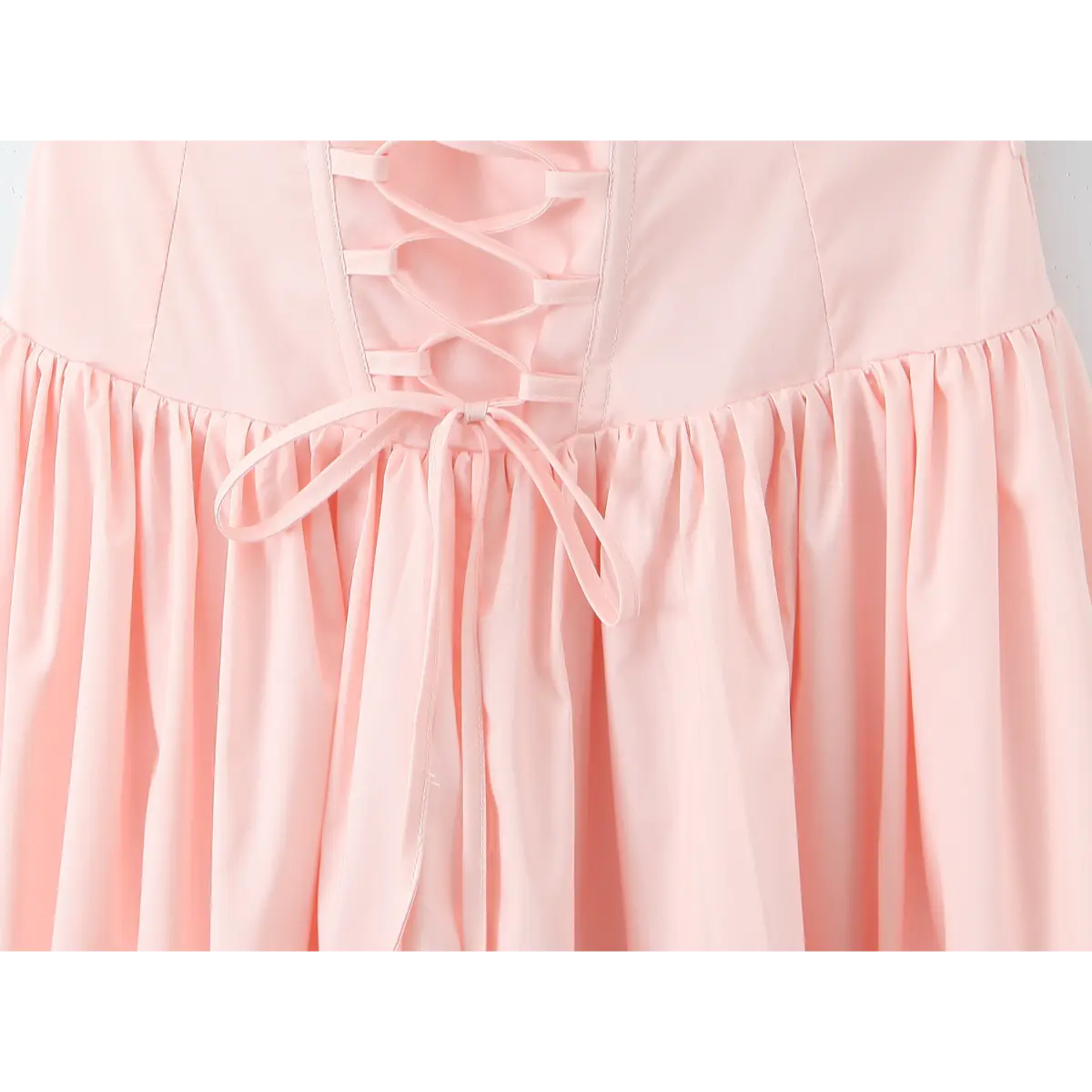 Close-up of the corset lace-up back detail on a light pink halter maxi dress, featuring gathered ties and a flared skirt.