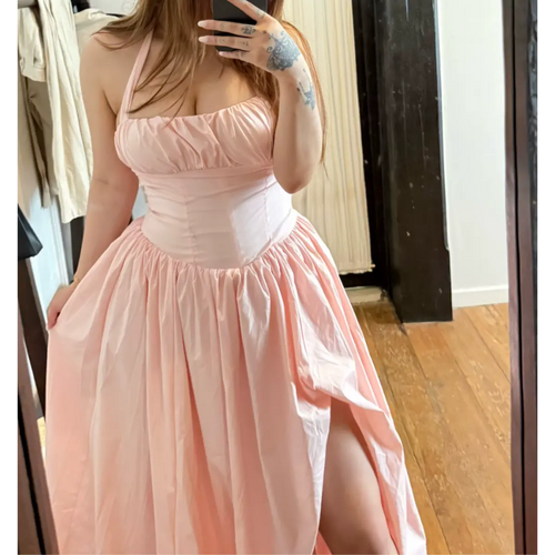 Mirror selfie of a woman wearing a light pink halter maxi dress, highlighting the gathered bust and structured corset waist.