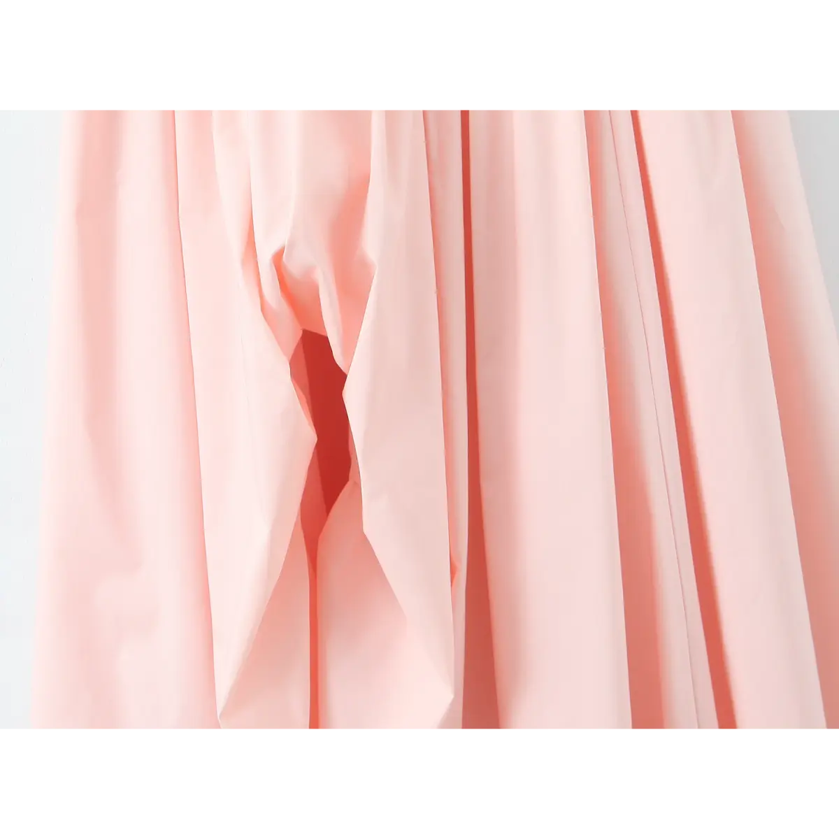 Close-up of the gathered skirt fabric on a light pink halter maxi dress, showing the texture and lining peek.
