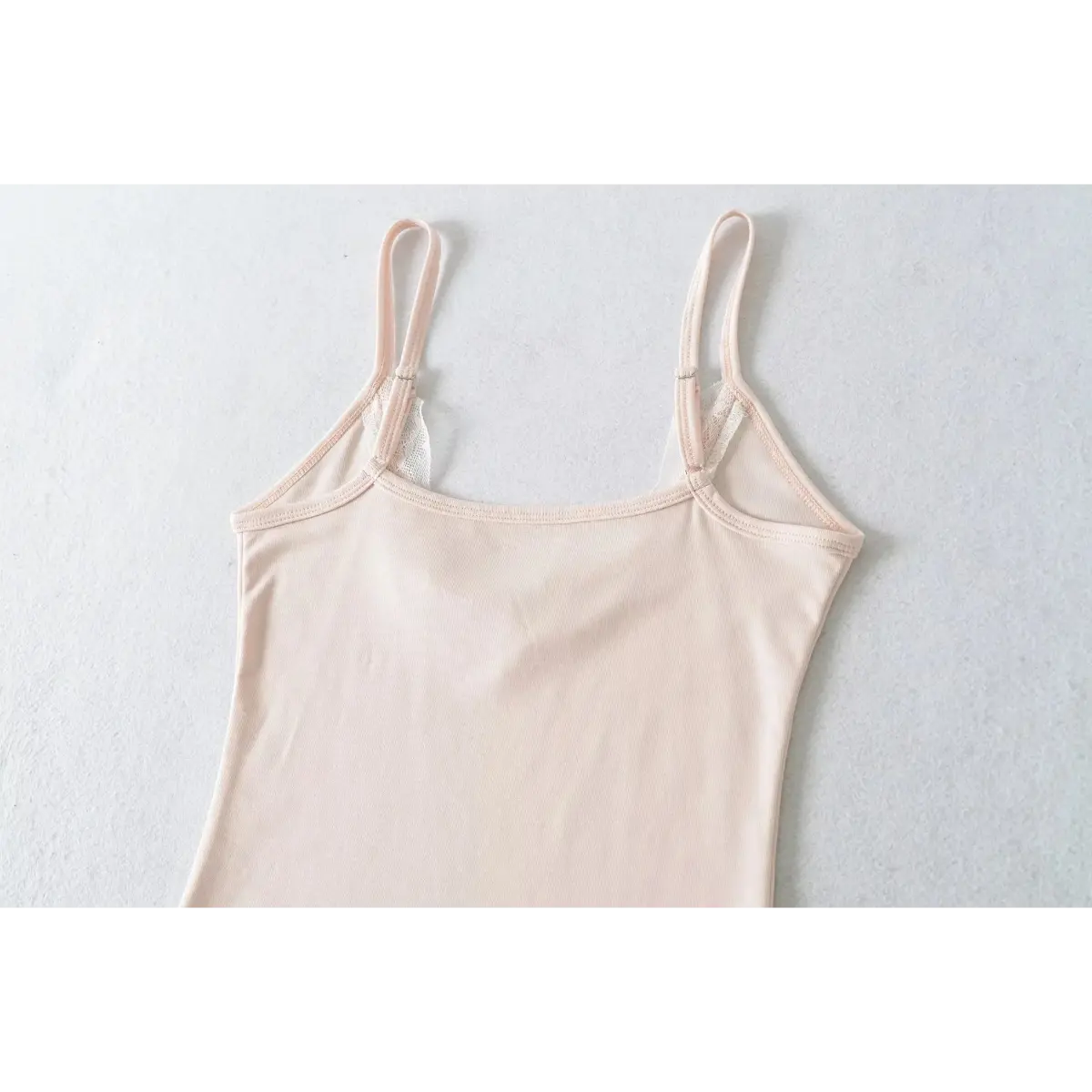 Back view of a light pink lace-trimmed cami top, showing adjustable spaghetti straps and the neat stitching at the neckline.