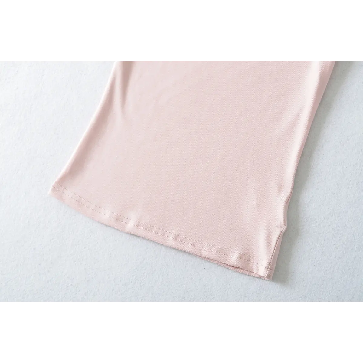 Close-up of light pink ribbed t-shirt's bottom hem, showing double-needle stitching