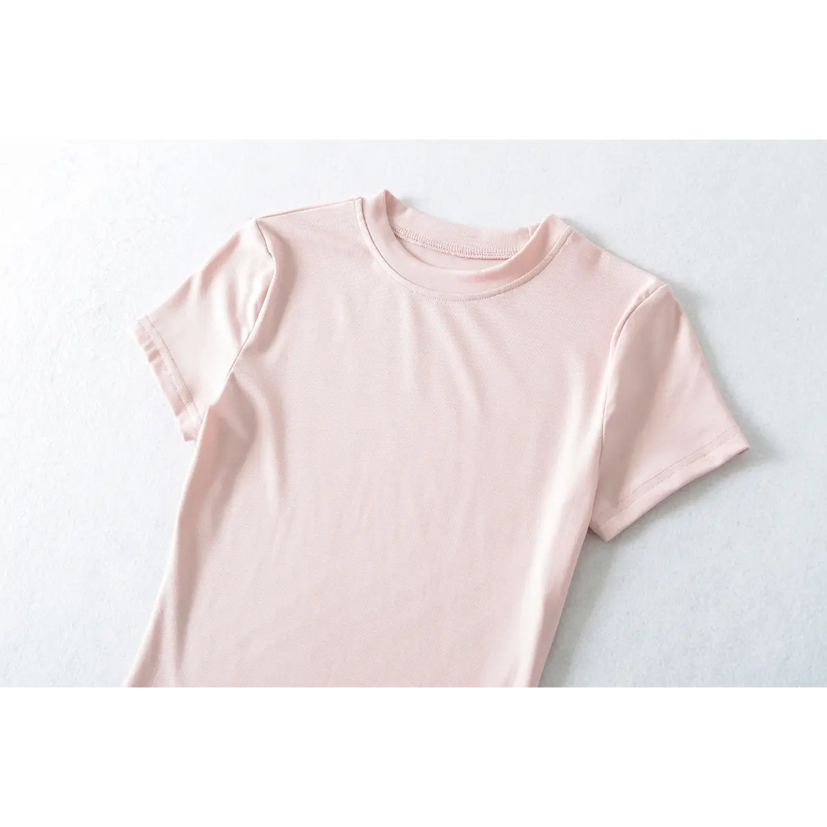 Partial front view of light pink ribbed t-shirt, showing crew neckline and shoulder seams