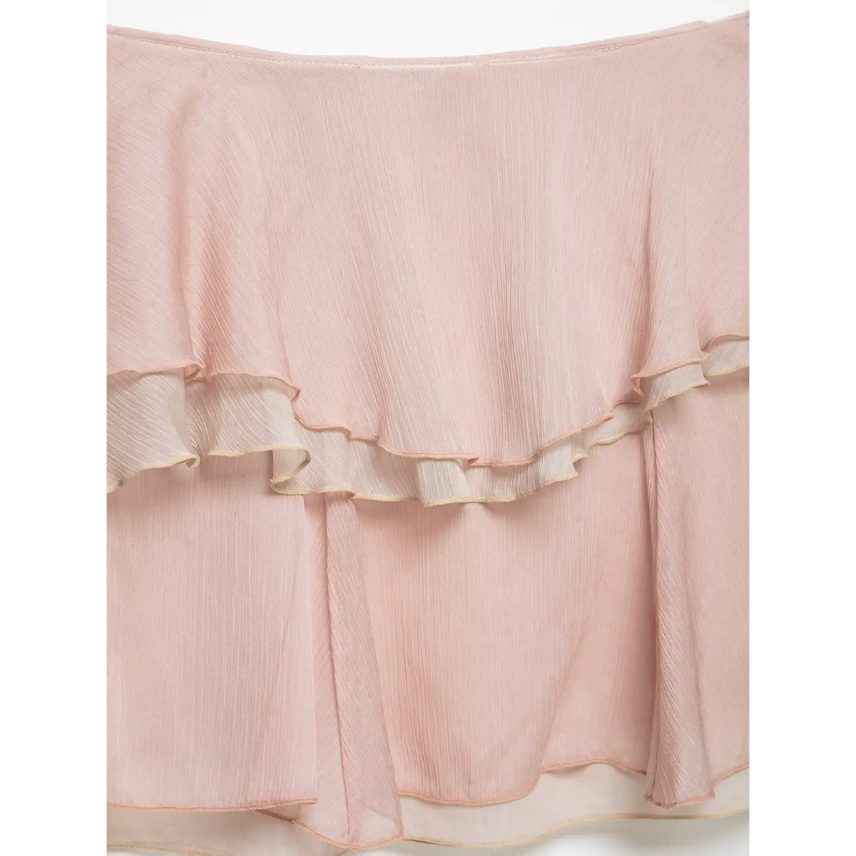 Flat close-up of light pink crinkled chiffon skirt, overlapping tiered ruffle, textured sheer fabric, white backdrop