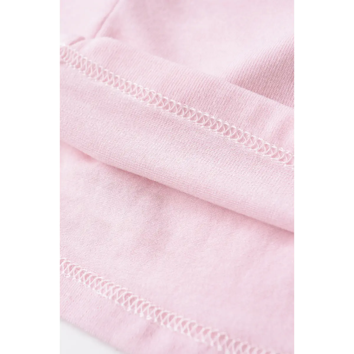 Close-up of the neatly stitched hem on the light pink stretch halter top.