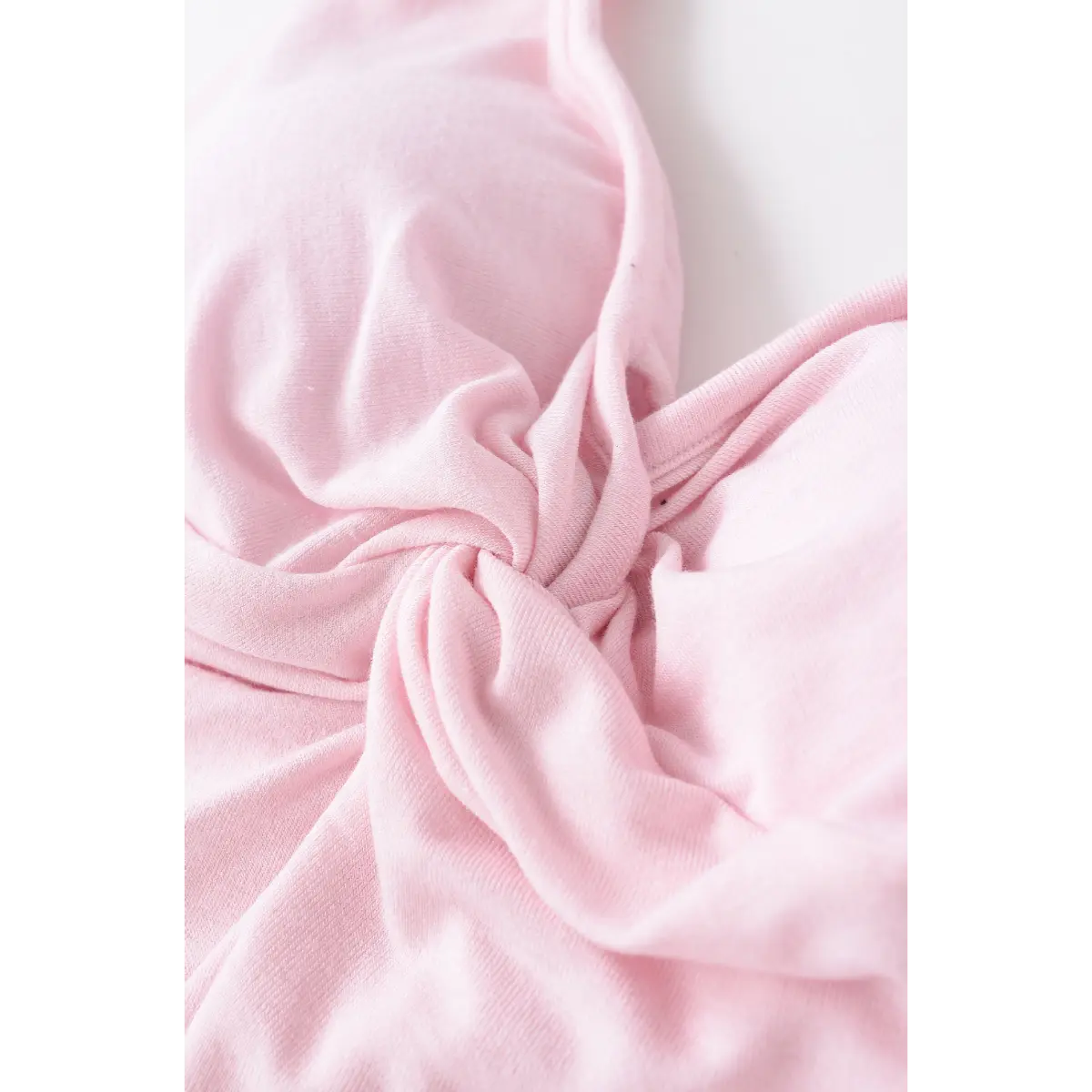 Close-up of the gathered twist detail at the center front of the light pink halter top.

