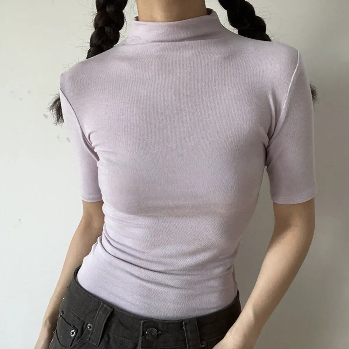 Lifestyle shot of form-fitting light purple ribbed half-turtleneck short-sleeve top, tucked into jeans