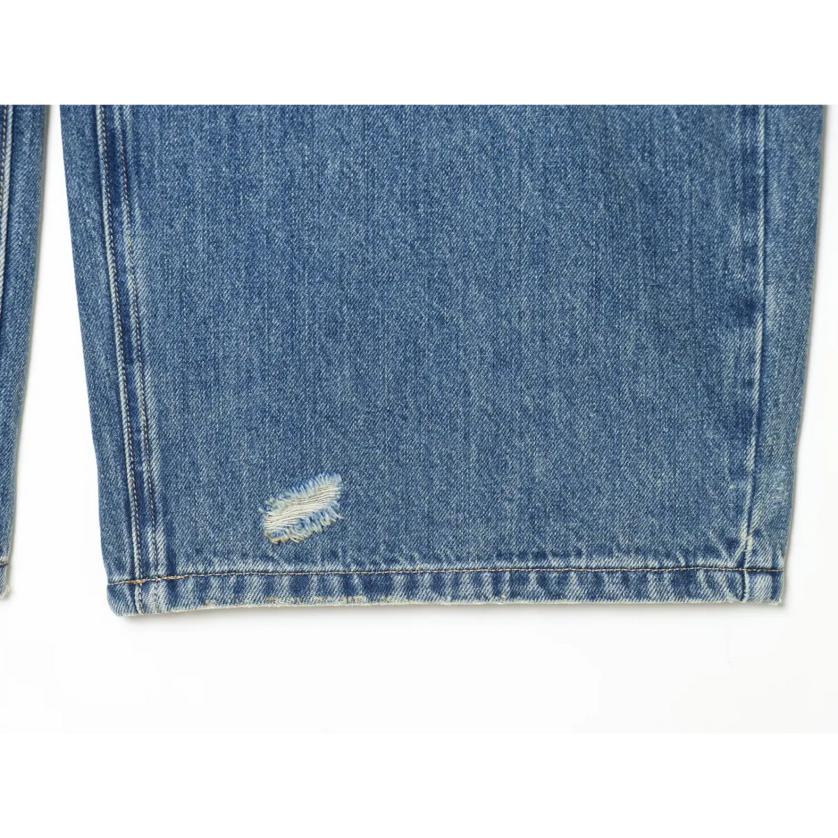 Close-up of jean hem with small frayed rip