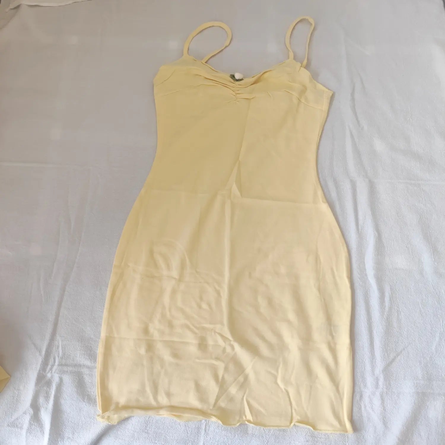 Flat lay top view pale yellow ruched bust spaghetti strap bodycon mini dress