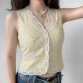 Lifestyle model shot light yellow sleeveless vest, scalloped eyelet lace trim v neck, white floral applique embroidery, slim cropped waistcoat layered outfit