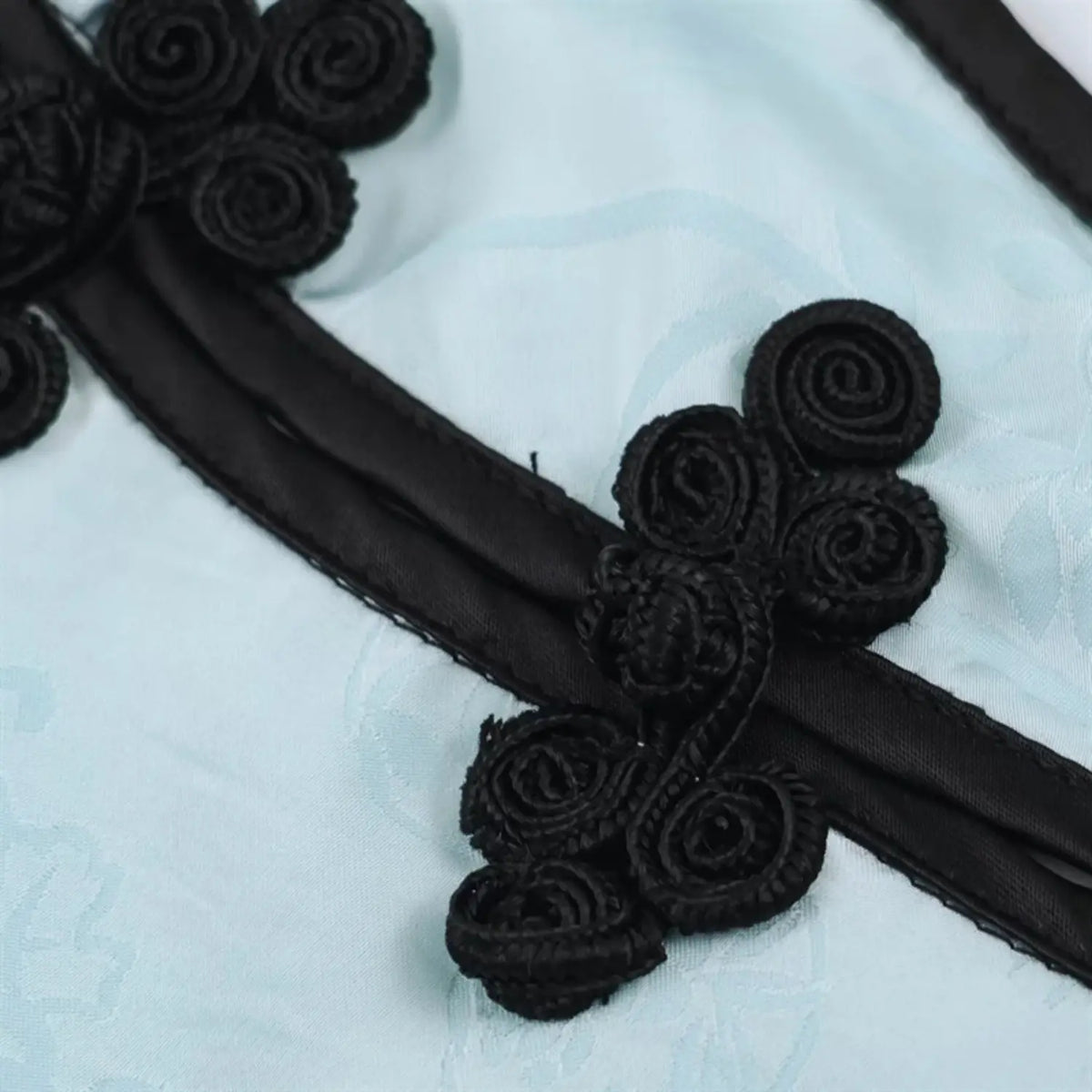 Detailed close‑up of black fabric frog buttons