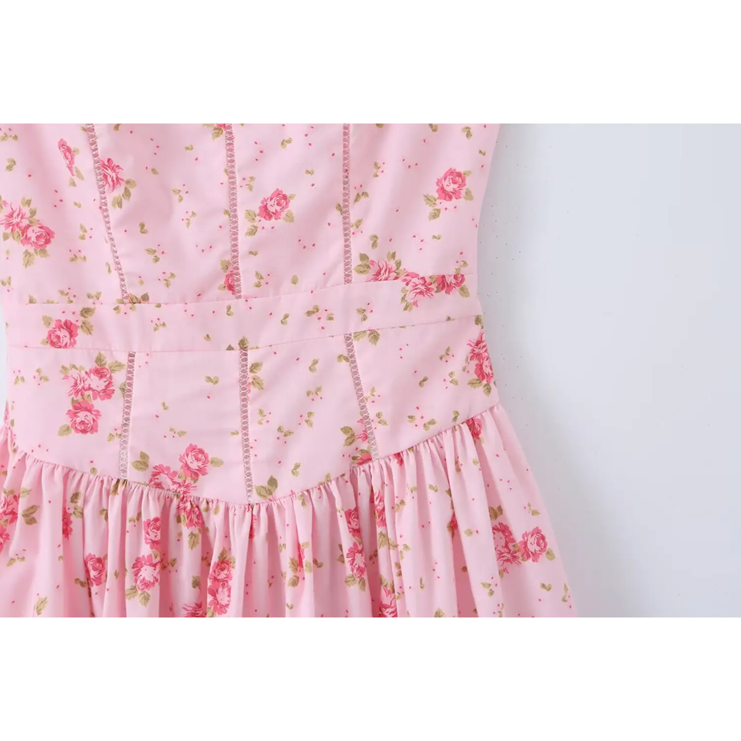 Close‑up view of light pink floral dress waist and bodice seam detail with rose print
