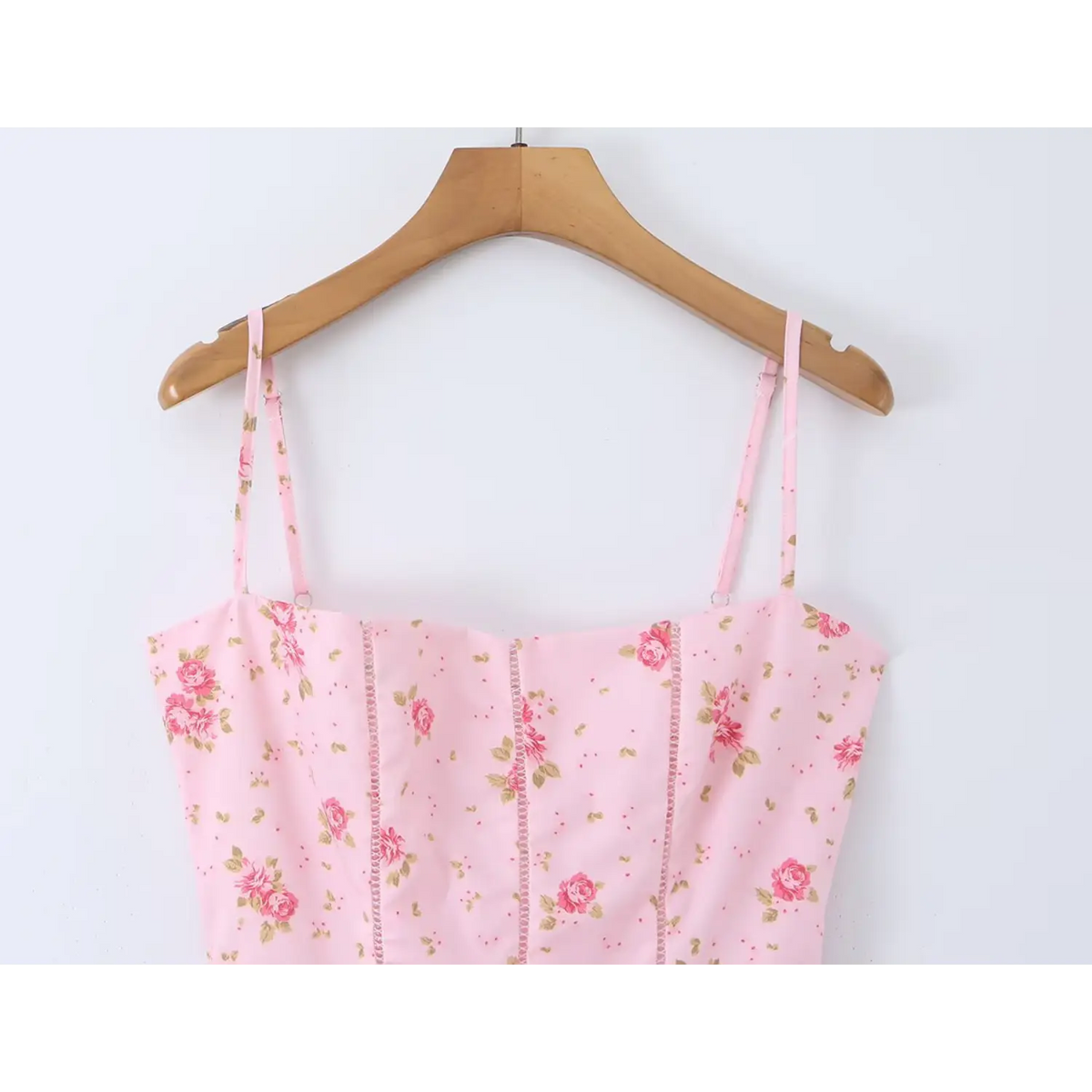 Close‑up of square neck bodice, light pink floral maxi dress on wooden hanger
