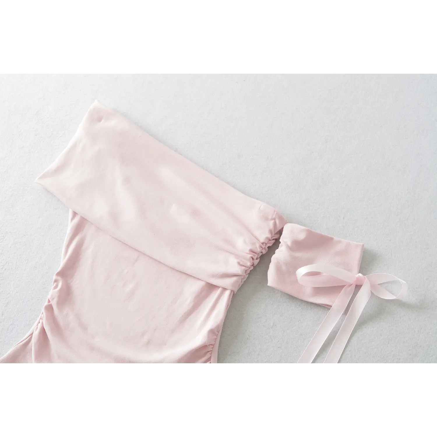 Light pink fold over off shoulder ruched crop top with separate satin ribbon bow short sleeve, full flat lay product shot white background