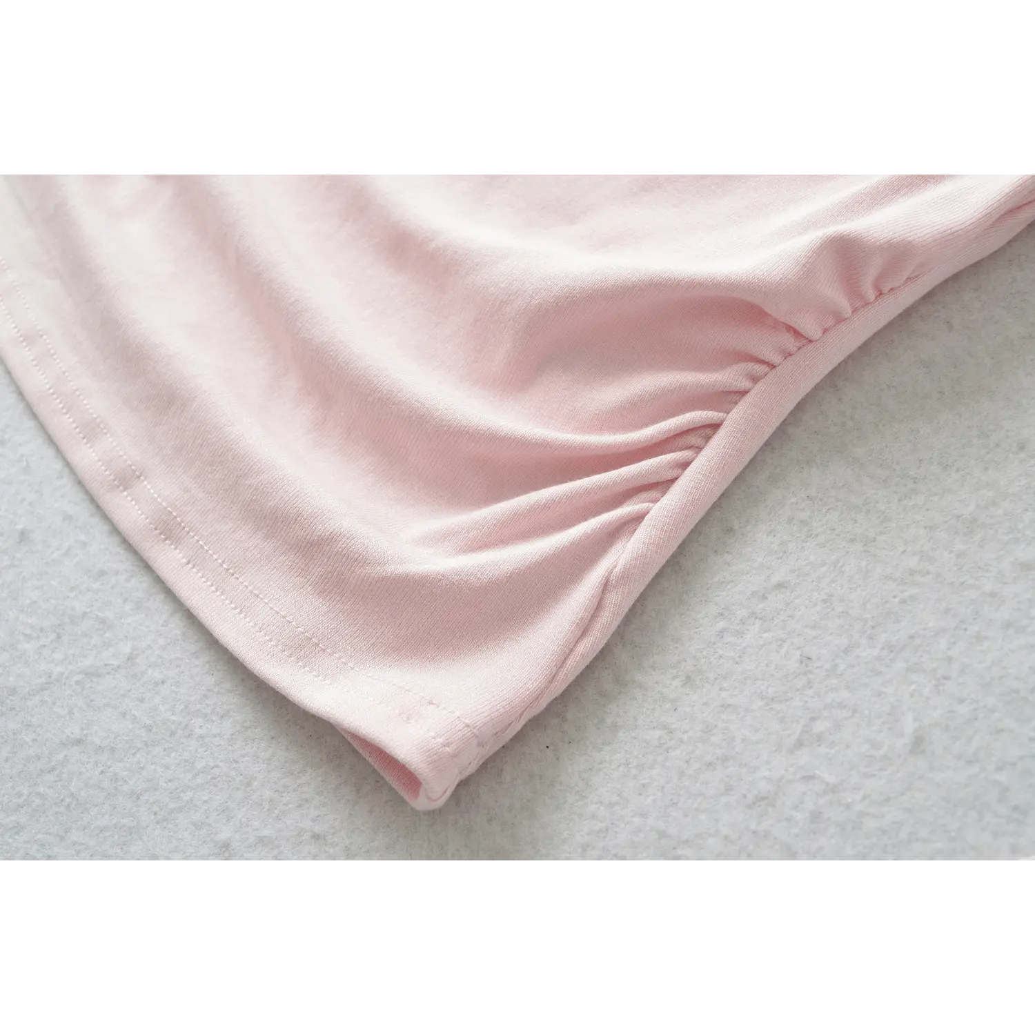 Close up texture shot of soft stretch knit fabric with side gathering ruching on pink off shoulder top