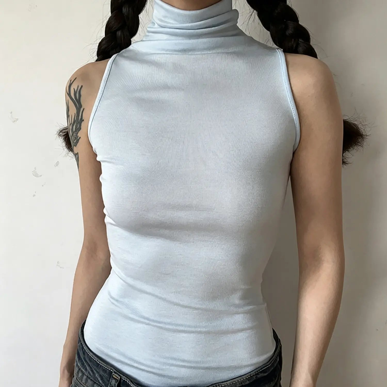 Front torso view, model in light blue sleeveless high turtleneck tank top, fitted cut