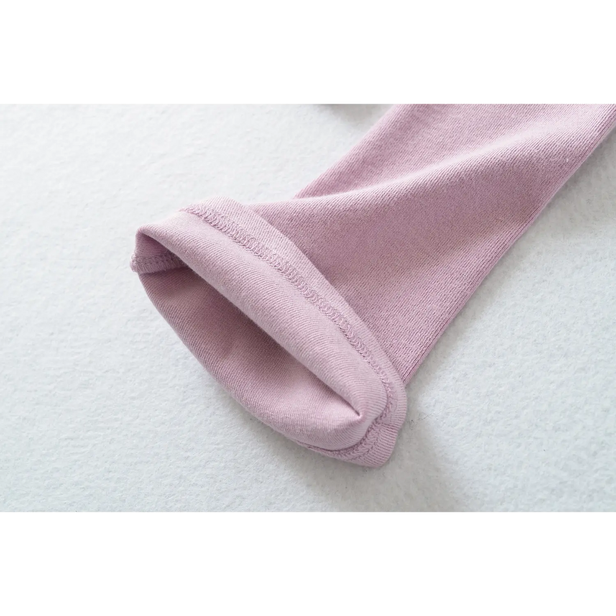 Close up of lilac stretch knit long sleeve top, showing flared sleeve cuff and neat finished stitching