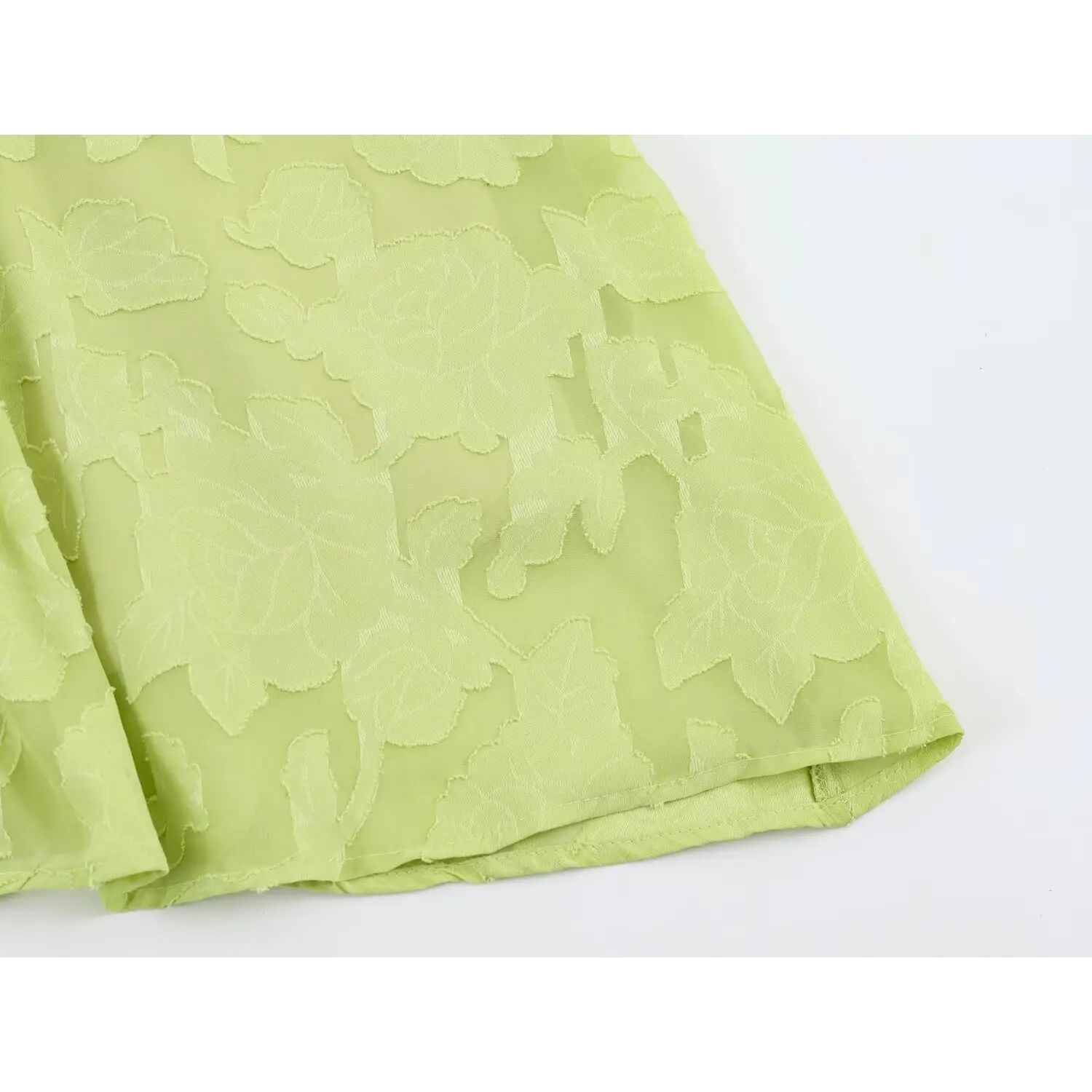 Flat skirt hem close-up of the single outer sheer layer, distinct outlined floral burnout print and smooth hem stitching