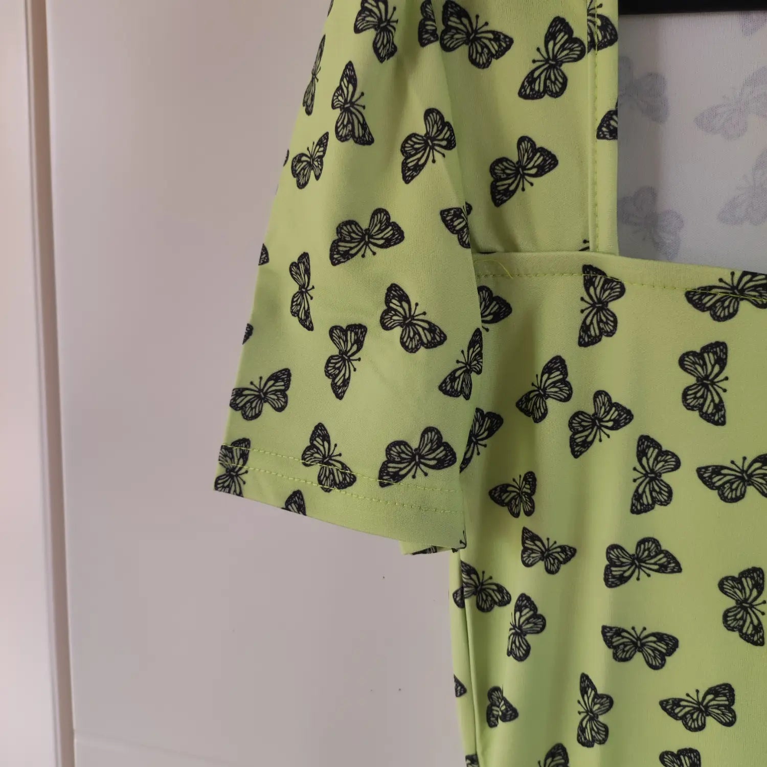 Close‑up short sleeve cuff stitching and fabric print detail lime green butterfly bodycon mini dress
