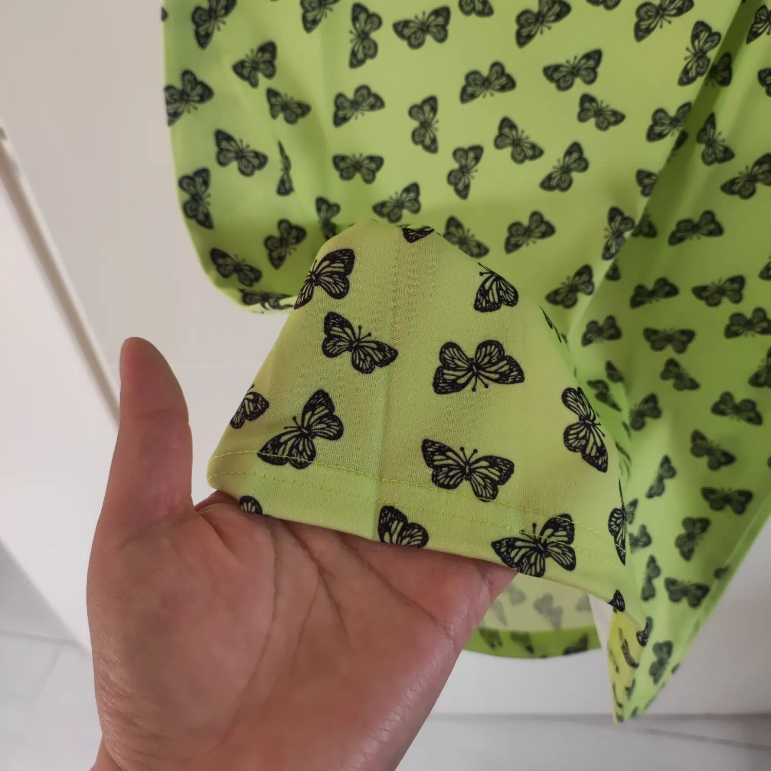 Close‑up bottom hem finished seam detail lime green butterfly print short sleeve mini dress