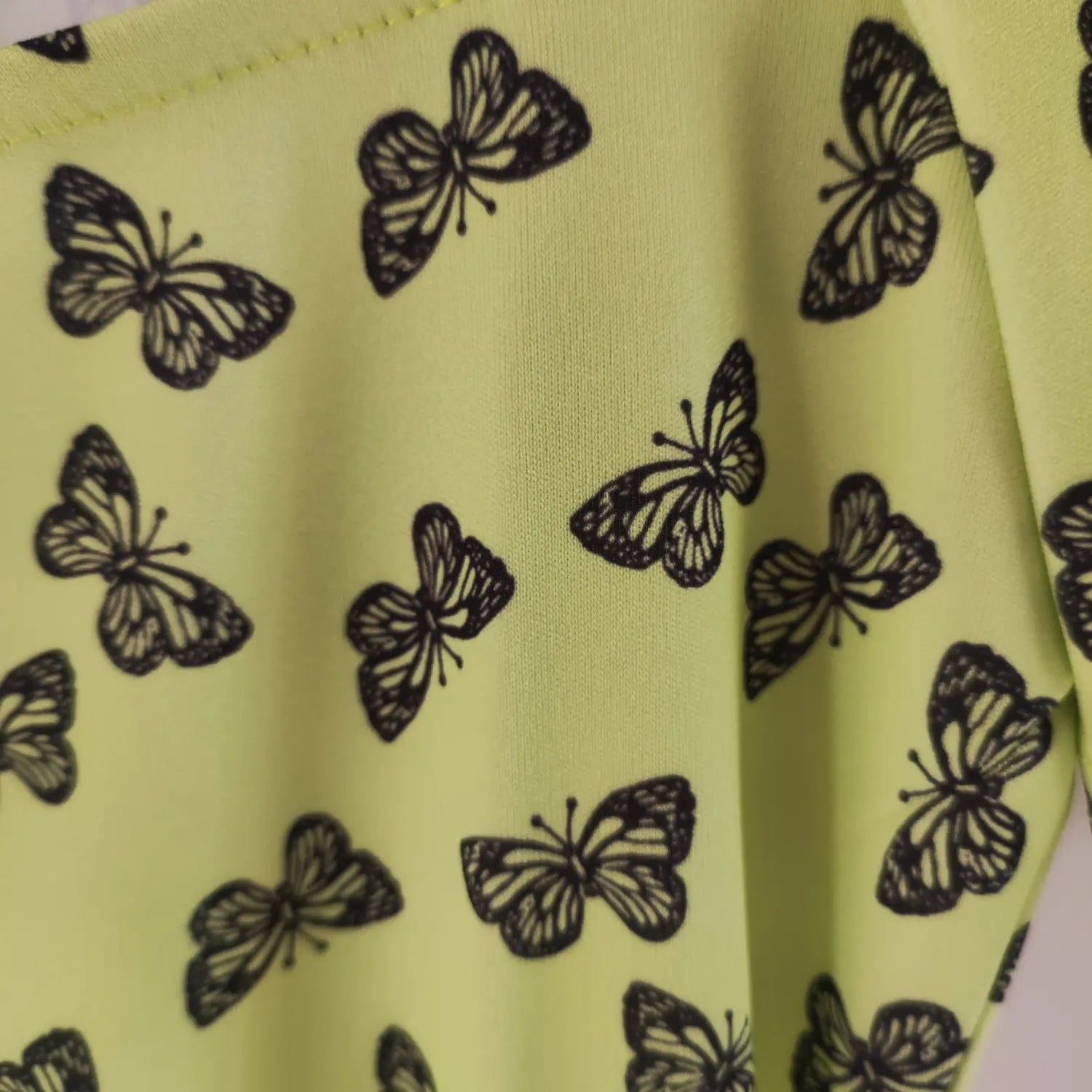 Macro close‑up fabric texture and black butterfly print pattern lime green bodycon mini dress