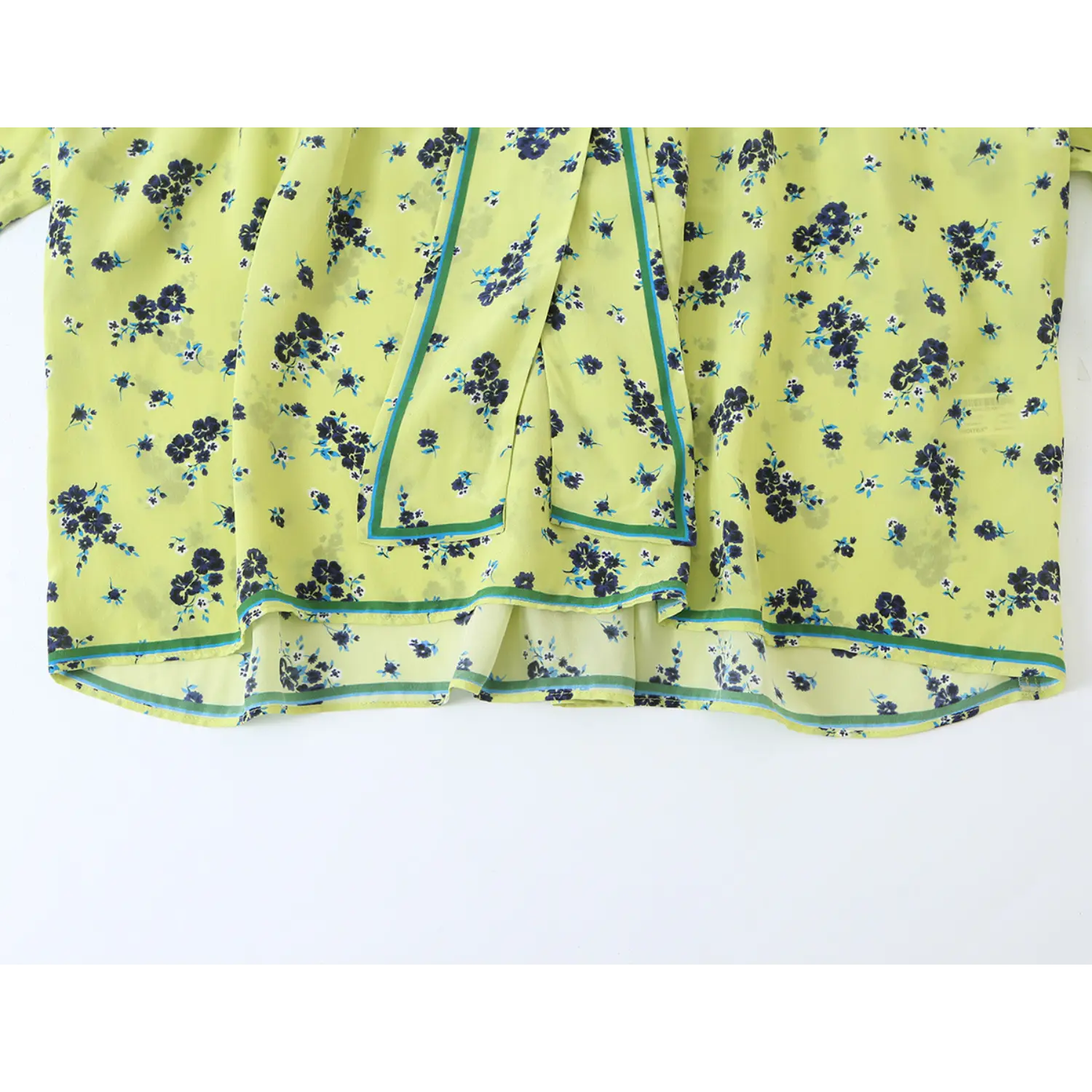 Full partial view front hem and contrast piping trim of lime green navy floral blouse