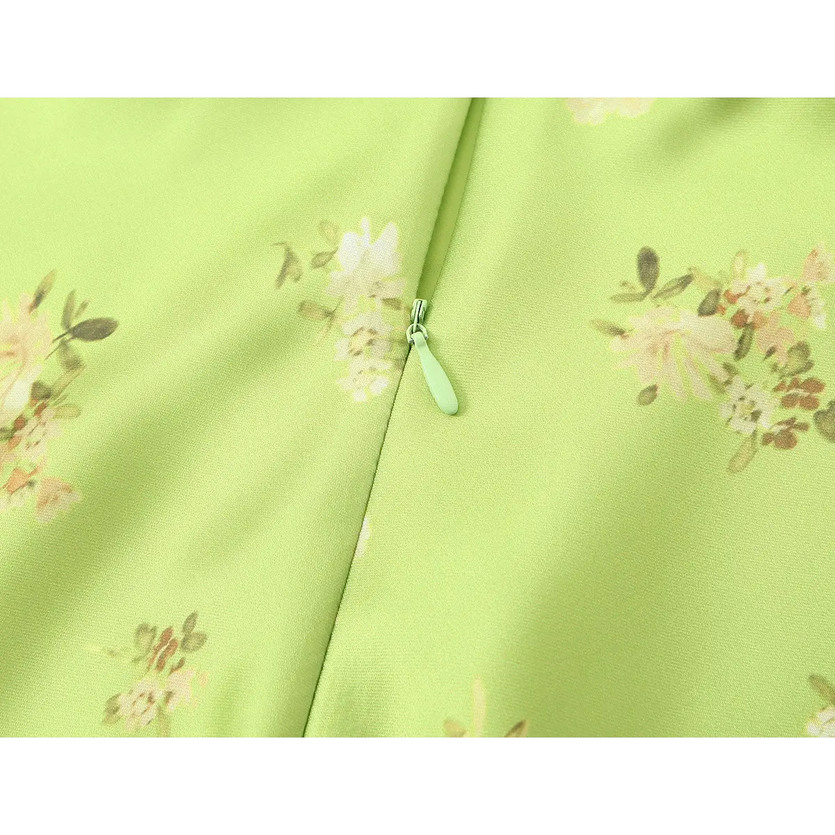 Close-up of the side zipper on the lime green floral satin dress, with a matching lime green pull