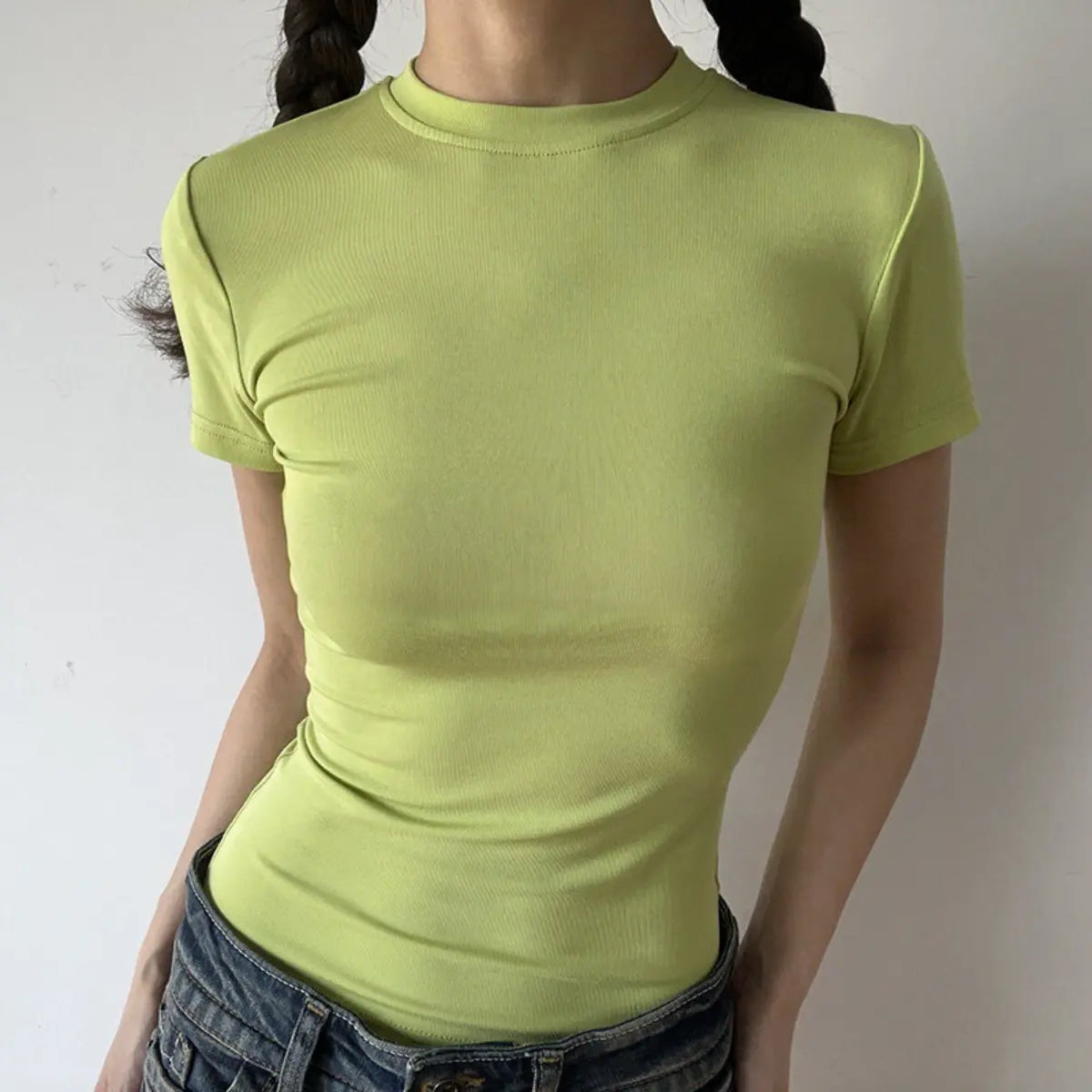 Lifestyle shot of form-fitting lime green ribbed crew-neck t-shirt, tucked into jeans
