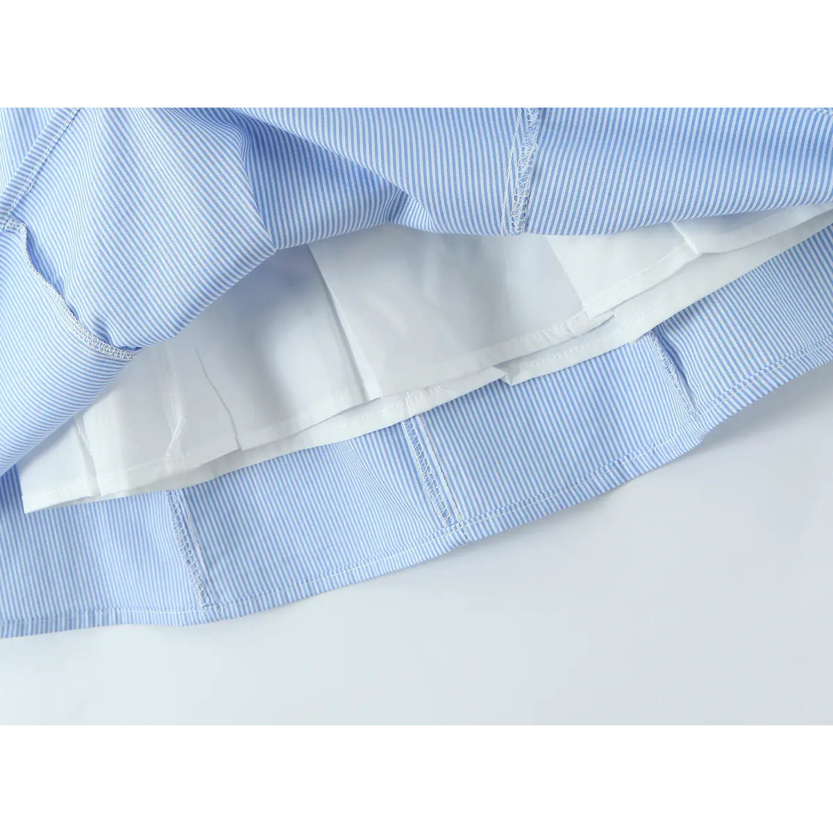 Close-up of the inner lining and finished hem on a blue and white striped halter dress, showing the construction and stitching details.