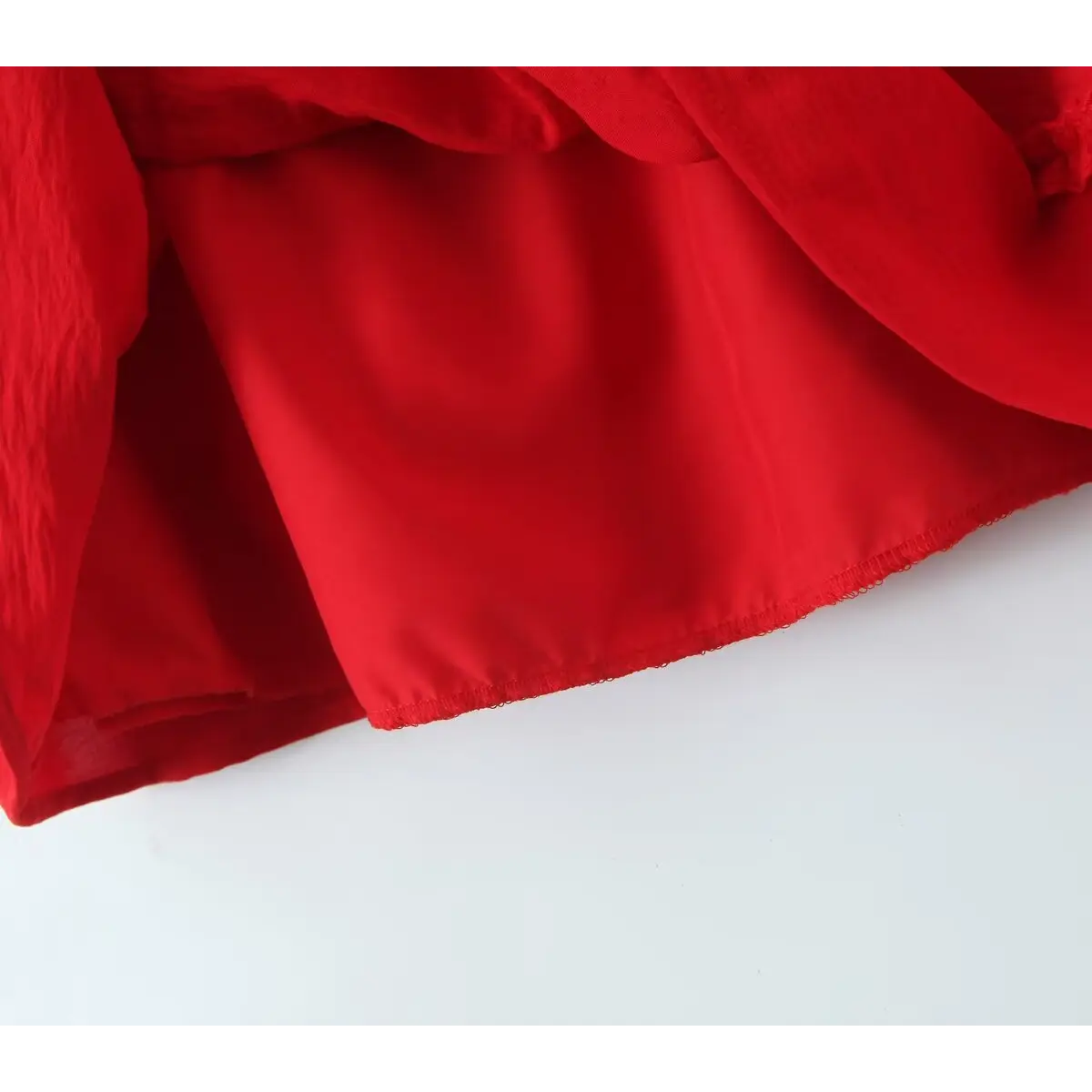  Close-up of the inner lining and hem on a red lace-trimmed cami dress, showing the smooth, opaque lining.
