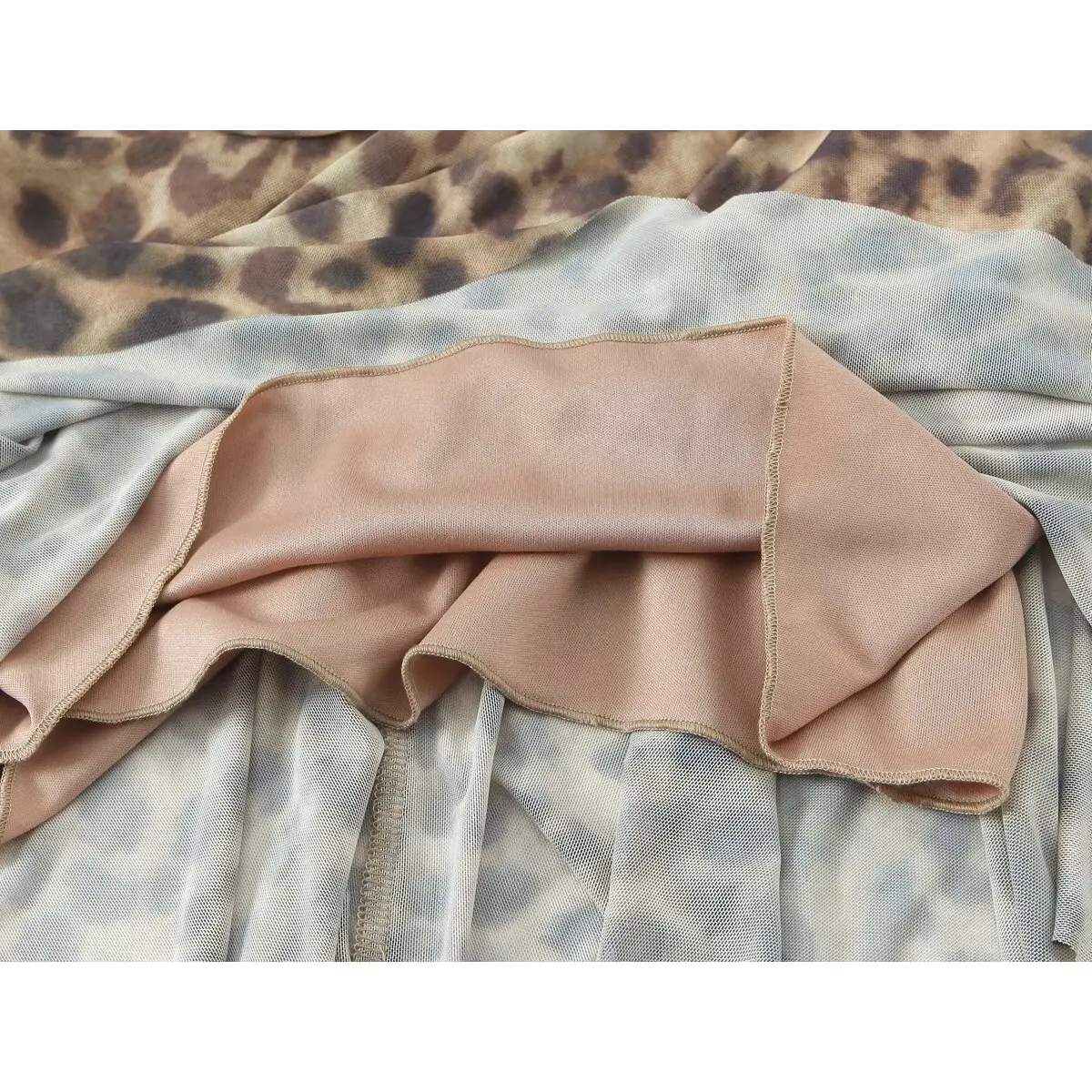 Close-up of the inner bust on a leopard print halter dress, revealing the nude lining and halter strap attachment.