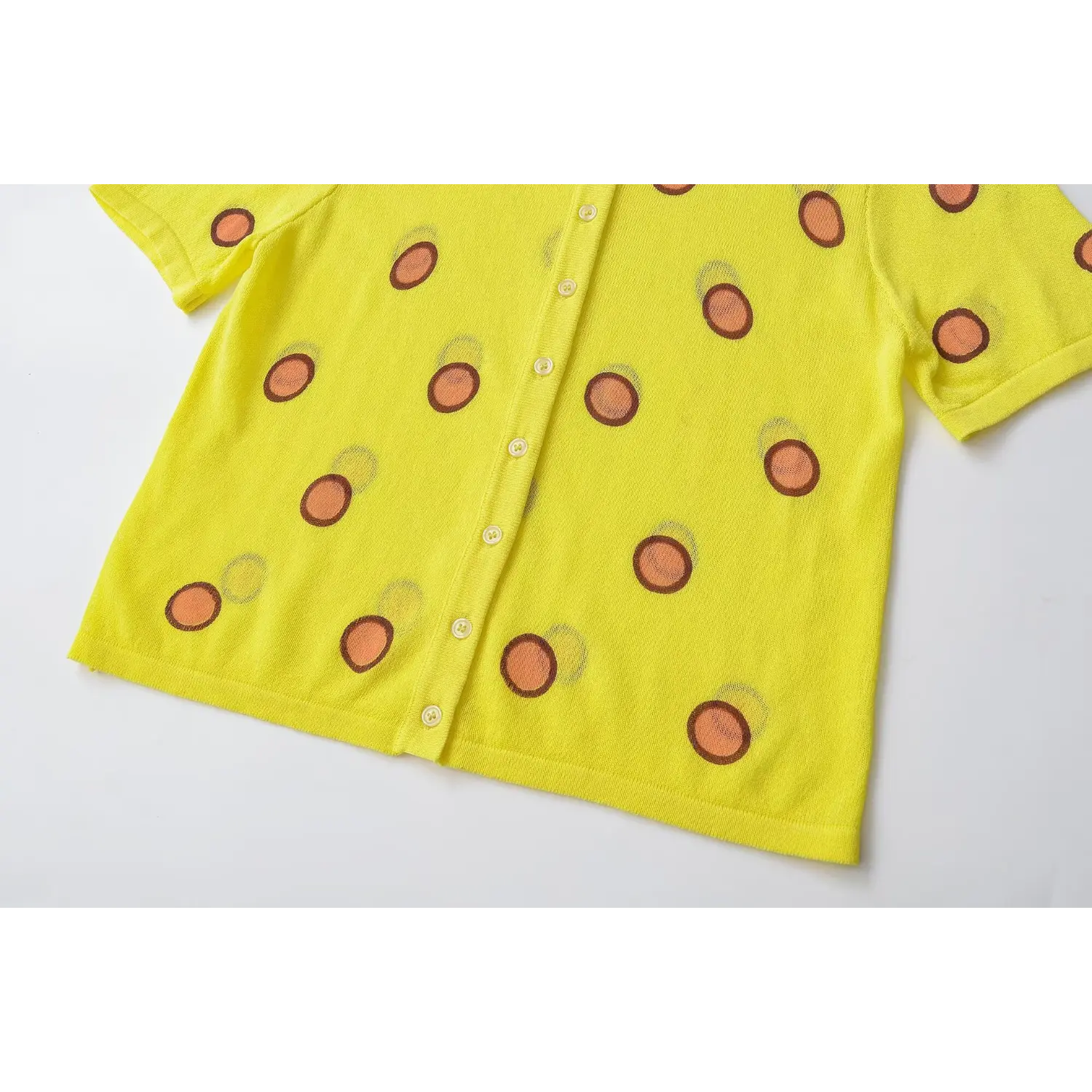 Lower torso flat partial shot, full button row, straight rib hem, continuous polka dot print
